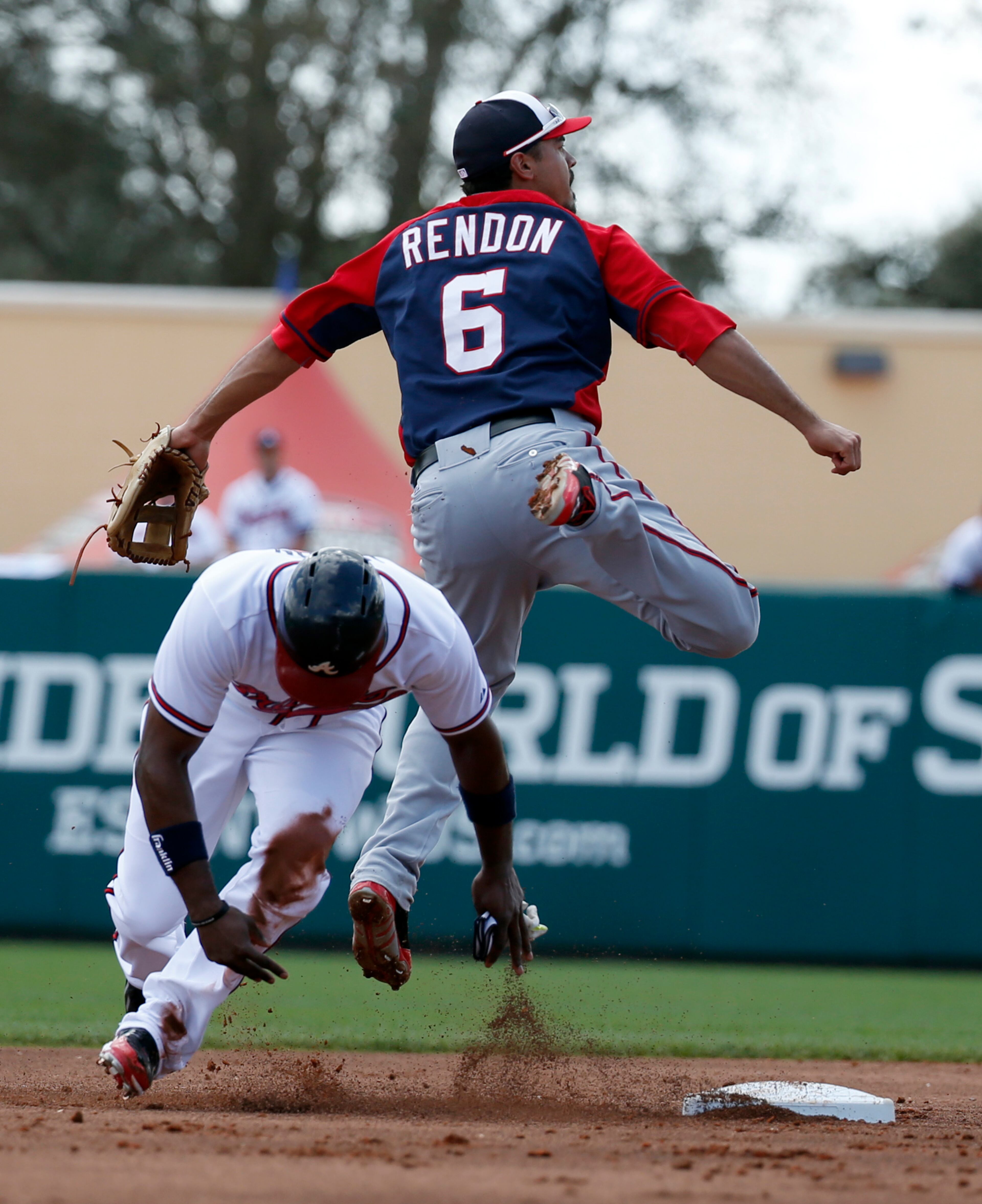 Washington Nationals second baseman Anthony Rendon (6) jumps over Atlanta Braves' Justin Upton (8) after getting the out at second and throwing to first base to complete the double play in the second inning of a spring exhibition baseball game, Tuesday, March 4, 2014, in Kissimmee, Fla.