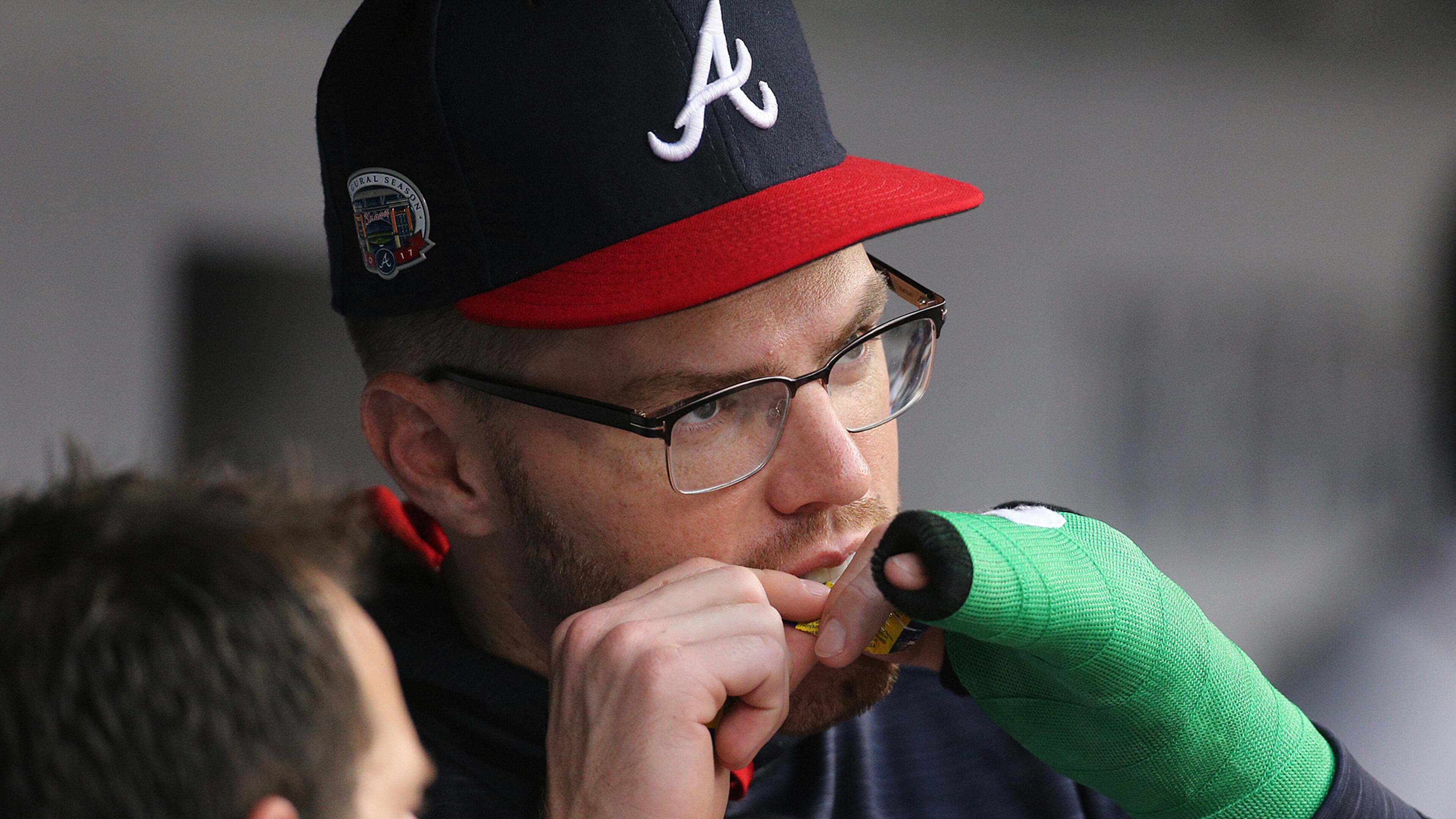 Atlanta Braves first baseman Freddie Freeman, whose wrist was broken Wednesday by a pitch from Toronto Blue Jays' Aaron Loop and is in a cast, opens a piece of bubble gum in the dugout during the first inning of the teams' baseball game Thursday, May 18, 2017, in Atlanta. (Curtis Compton/Atlanta Journal-Constitution via AP)