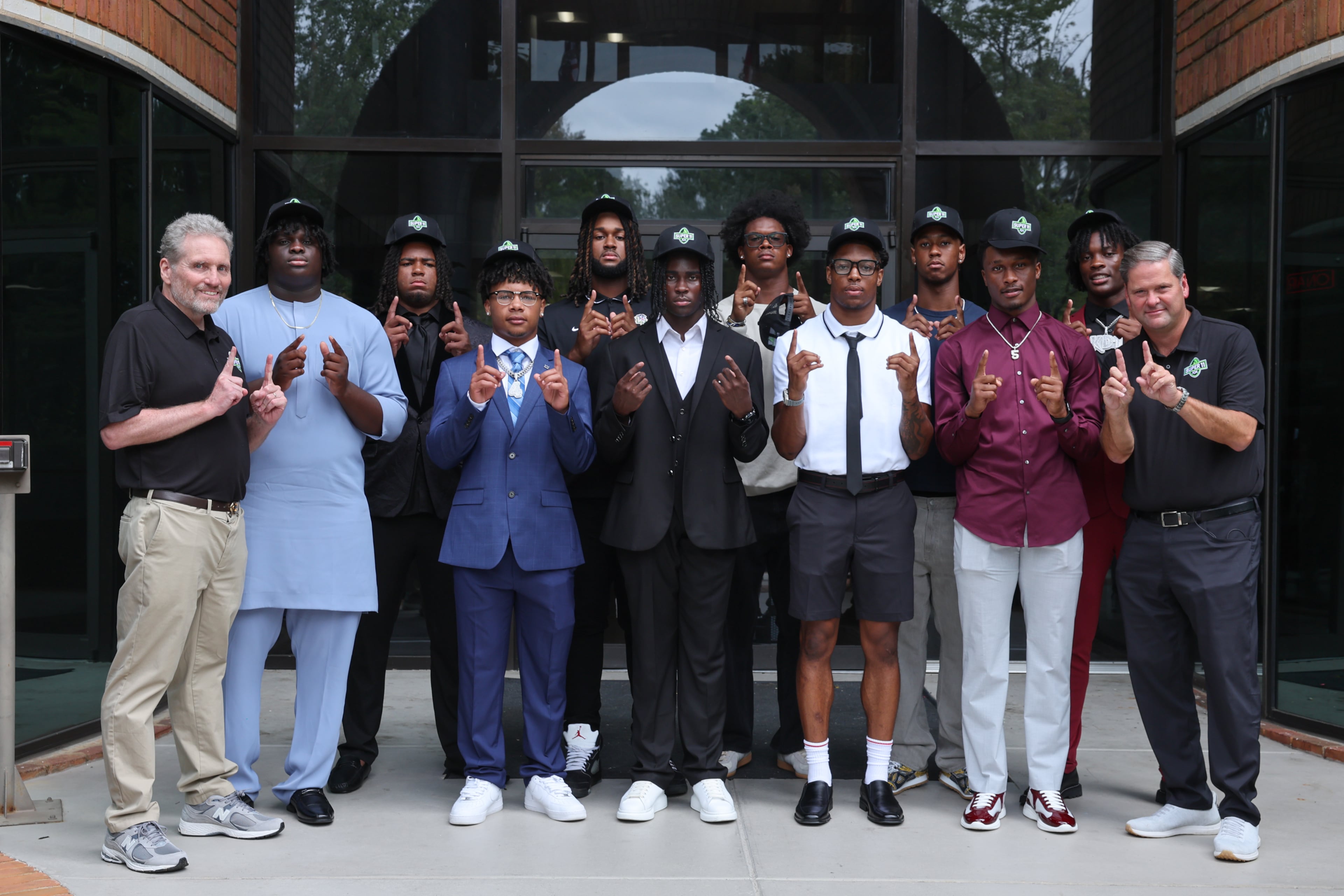 The Super 11 Class of 2026 (except for Quinterrius “Moonie” Gipson) along with DawgNation’s Brandon Adams and AJC’s Todd Holcomb pose for a portrait at the Super 11 reveal show at Score ATL in Roswell on Aug. 3, 2026. (Arvin Temkar/AJC)
