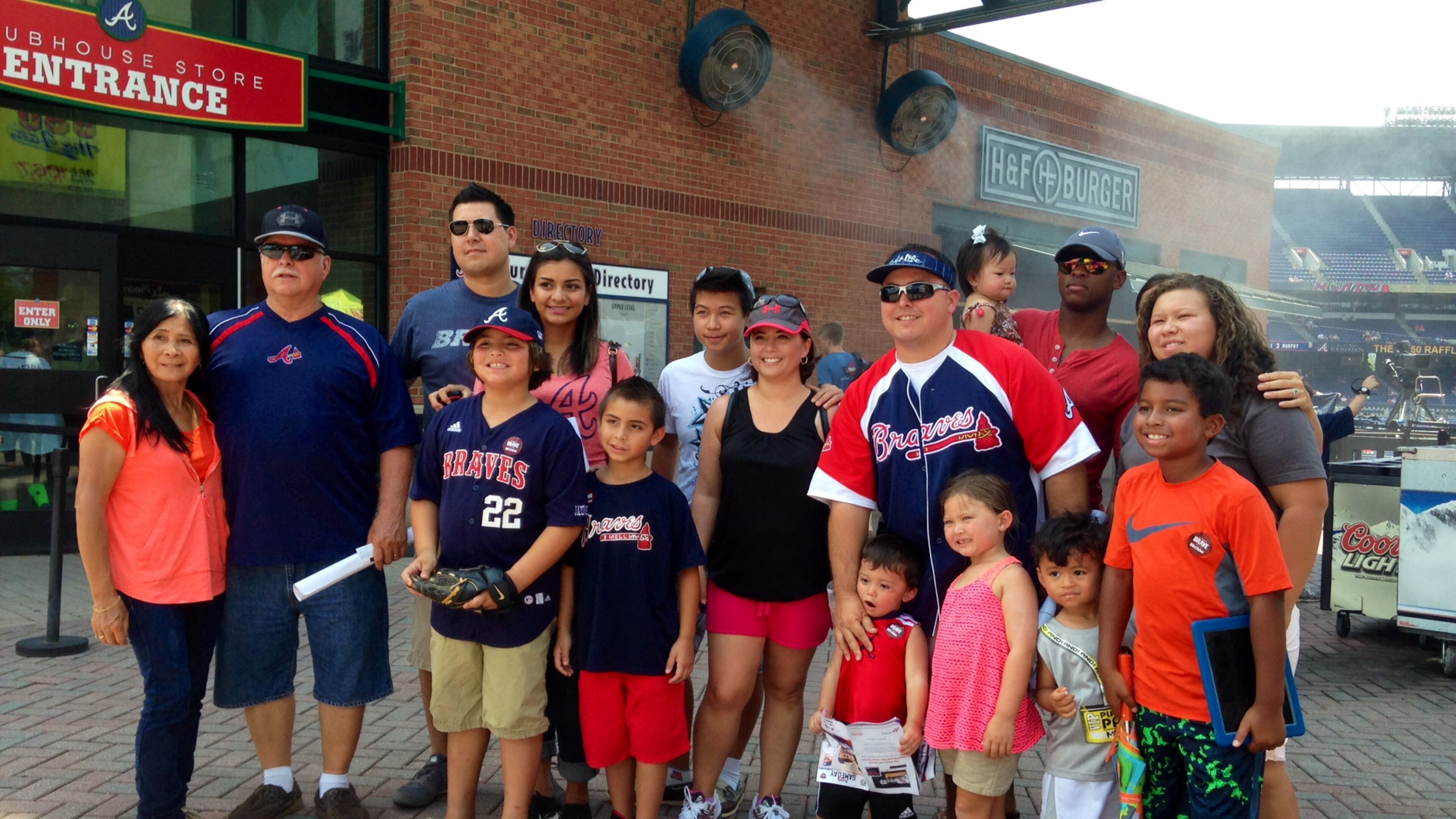 Joe Raymond (on the right with Braves jersey, cap and sunglasses) poses with about 18 of his family members before Sunday’s Hall of Fame induction screening at Turner Field. (Erica A. Hernandez/ehernandez@ajc.com)