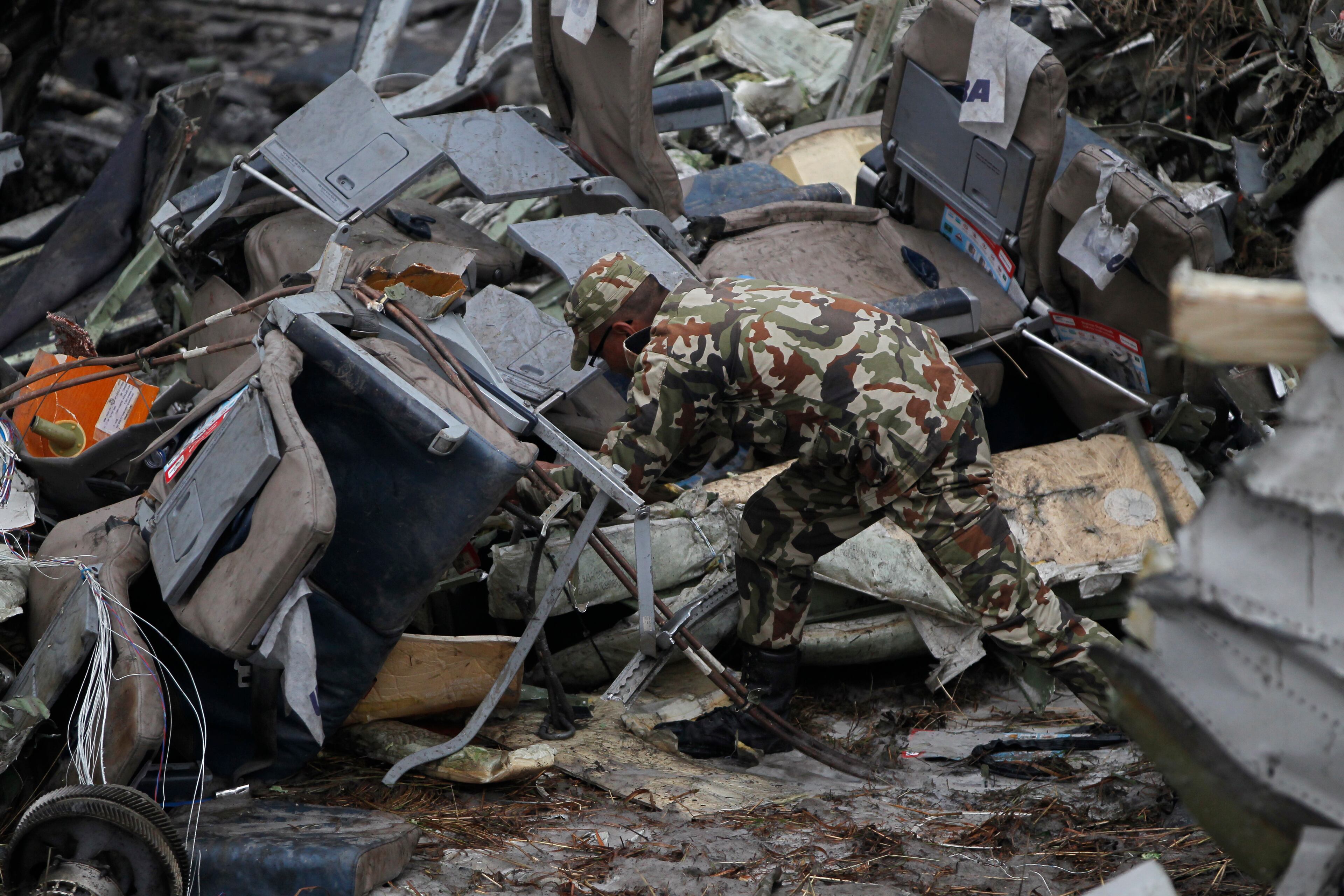 A Nepalese rescuer searches amid the debris after a passenger plane from Bangladesh crashed at the airport in Kathmandu, Nepal, Monday, March 12, 2018. The passenger plane carrying 71 people from Bangladesh crashed and burst into flames as it landed Monday in Kathmandu, Nepal's capital, killing dozens of people, officials said. (AP Photo/Niranjan Shreshta)