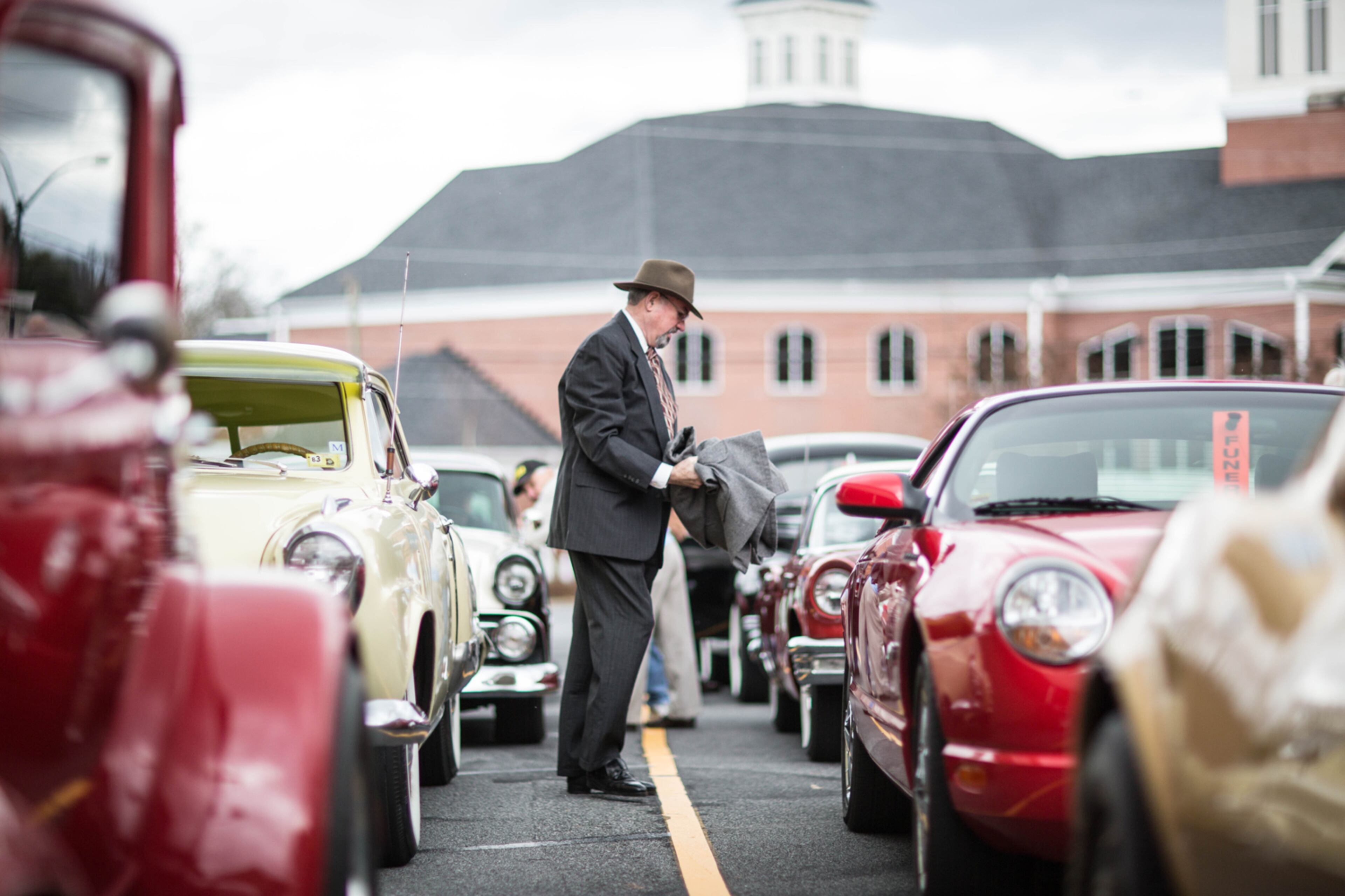 SENDOFF FOR SLAIN COUPLE--Alan Ziglin, member of the classic car group, ROMEO, walks between a row of classic cars, Monday, Feb. 2, 2015 in Marietta, Ga. Members of the group drove classic cars in the burial procession of Bud and June Runion to a national cemetery in Canton. The Runion's were allegedly slain while responding to a Craigslist ad for a vintage car. (SPECIAL/BRANDEN CAMP)