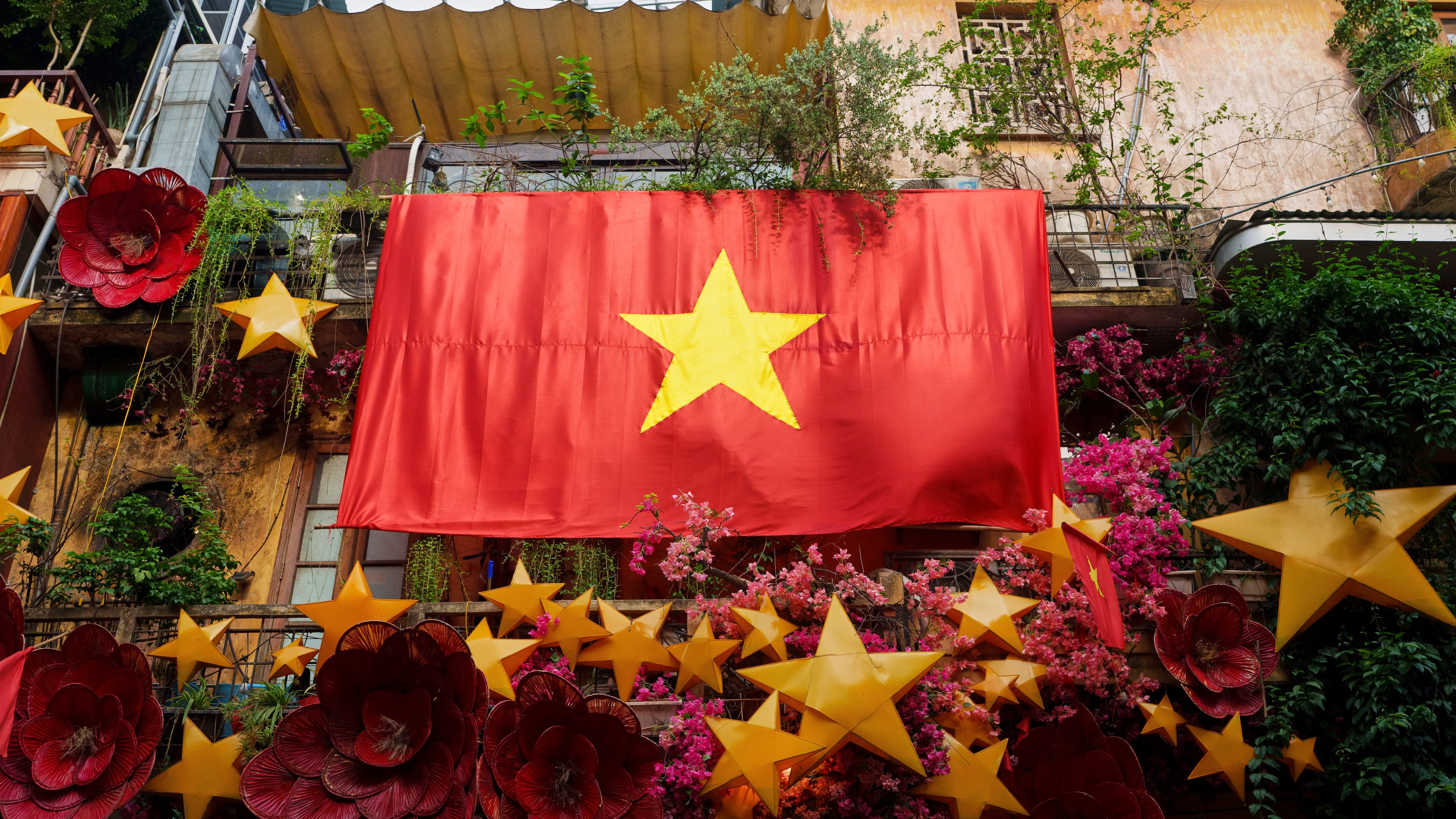 FILE - A giant Vietnamese national flag hangs from a balcony in the old quarter of Hanoi, Vietnam, Monday, Sept. 1, 2025. (AP Photo/Vincent Thian, File)