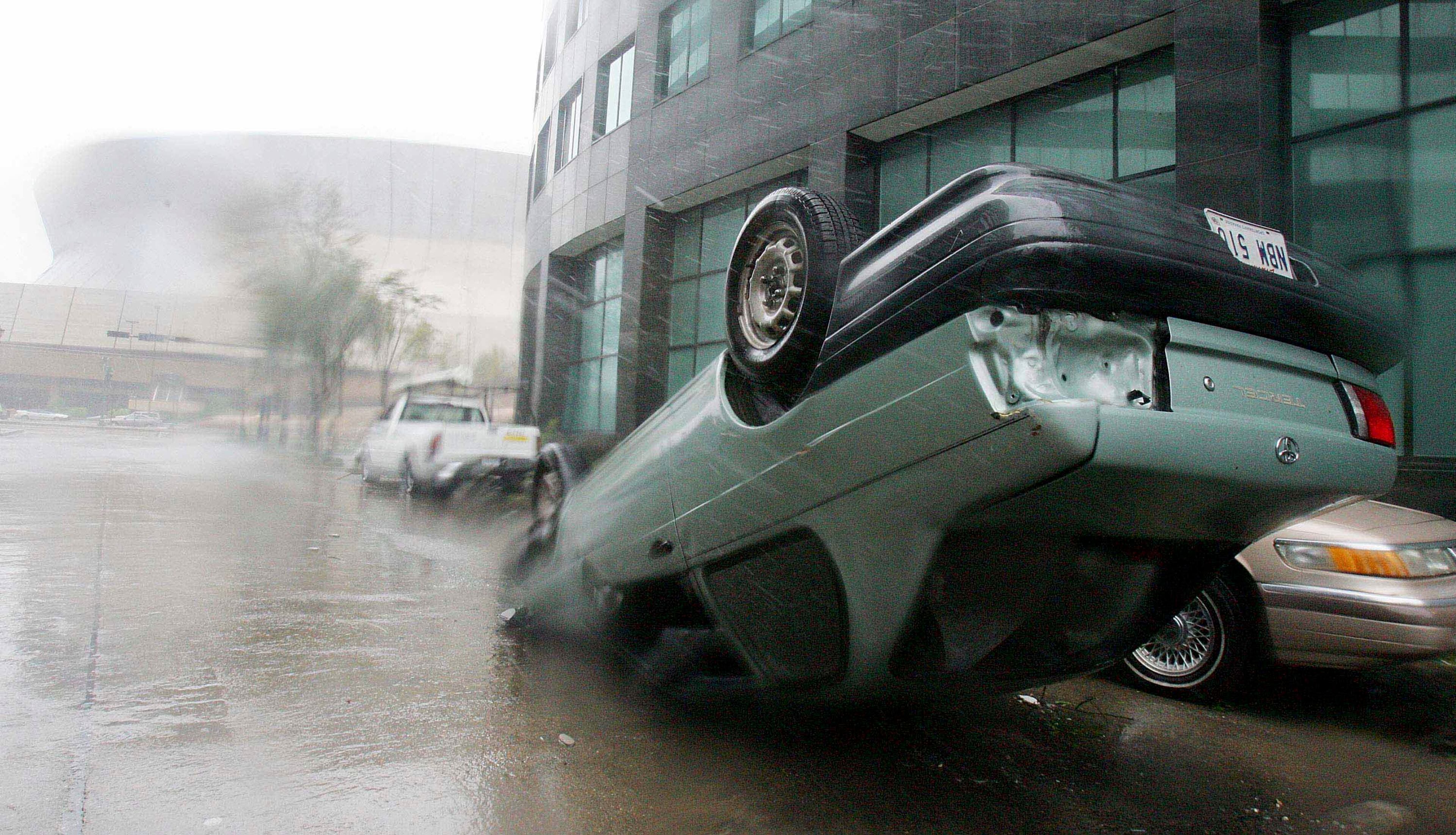 An overturned car sits in front of the Superdome in the aftermath of Hurricane Katrina August 29, 2005 in New Orleans, Louisiana. Katrina made landfall just east of the city at about 6:00 am (EST) with winds of over 140 mph. (Photo by Mario Tama/Getty Images)