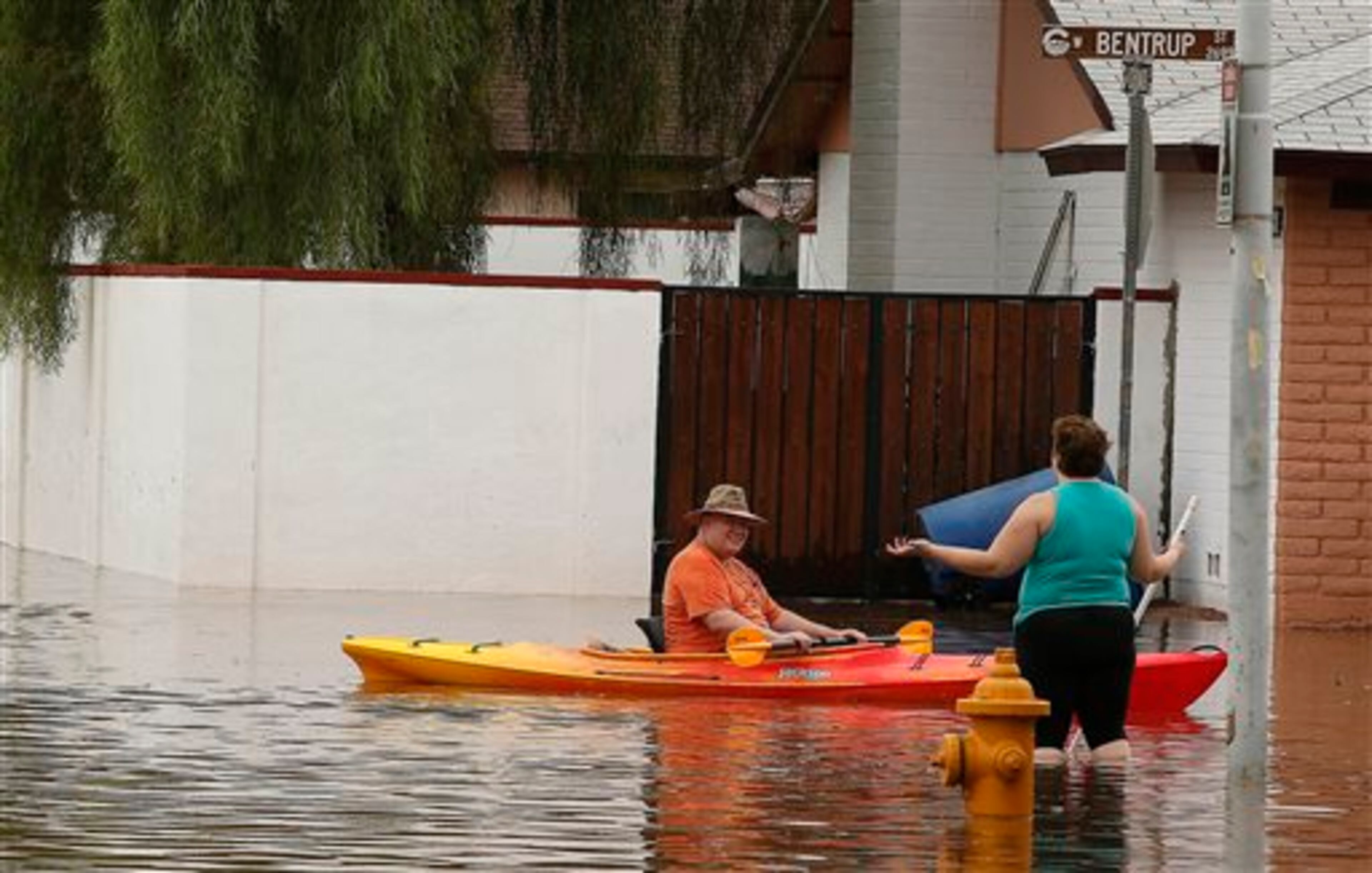 Two residents of a Chandler neighborhood talk in a flooded street after record breaking rains closed streets, highways and schools Monday, Sept. 8, 2014, in Chandler, Ariz. (AP Photo/Darryl Webb)