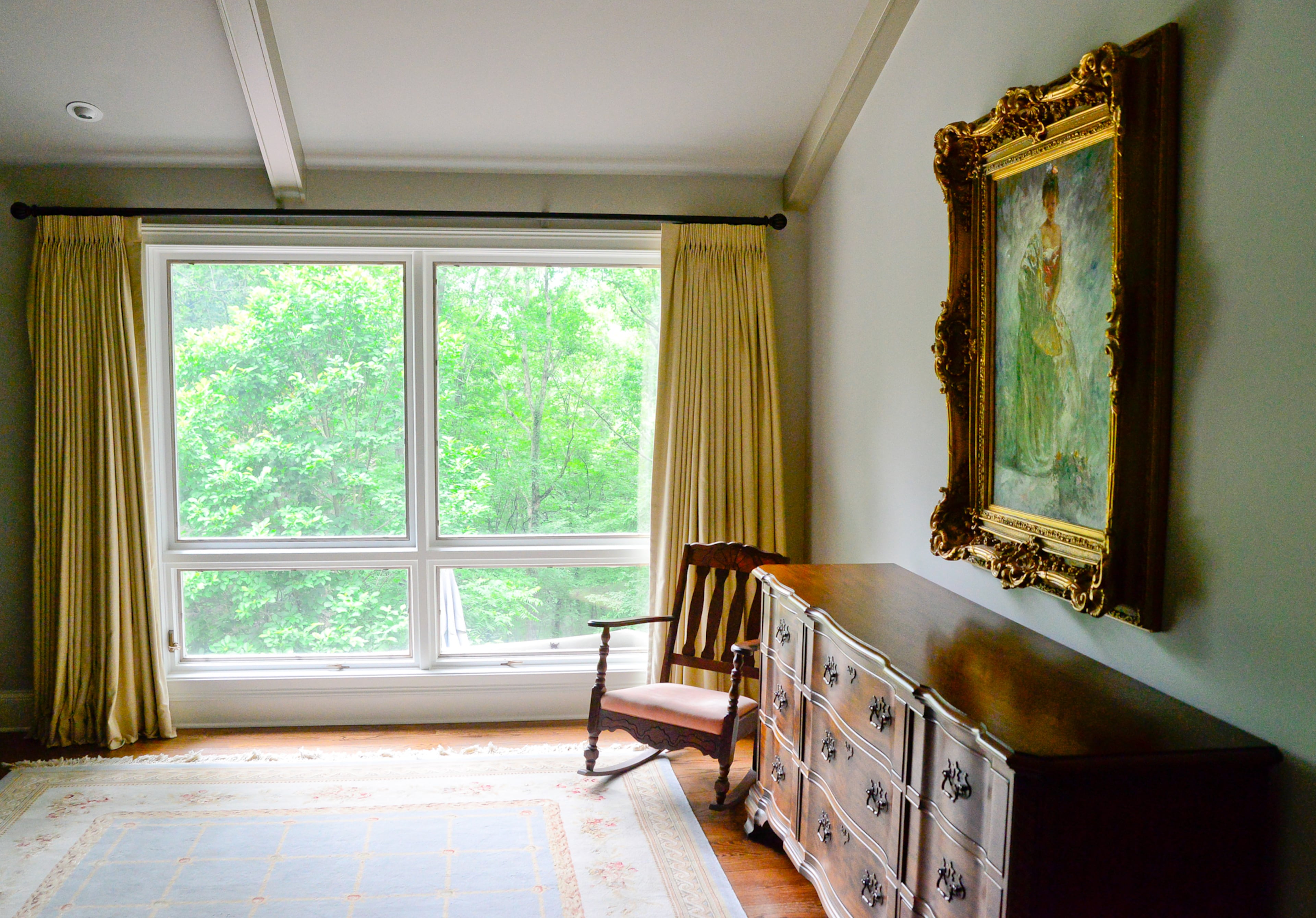 Two large windows allow the homeowners to view their garden from the master bedroom, which has a framed portrait by an unknown artist and purchased at a gallery on the Marietta Square.