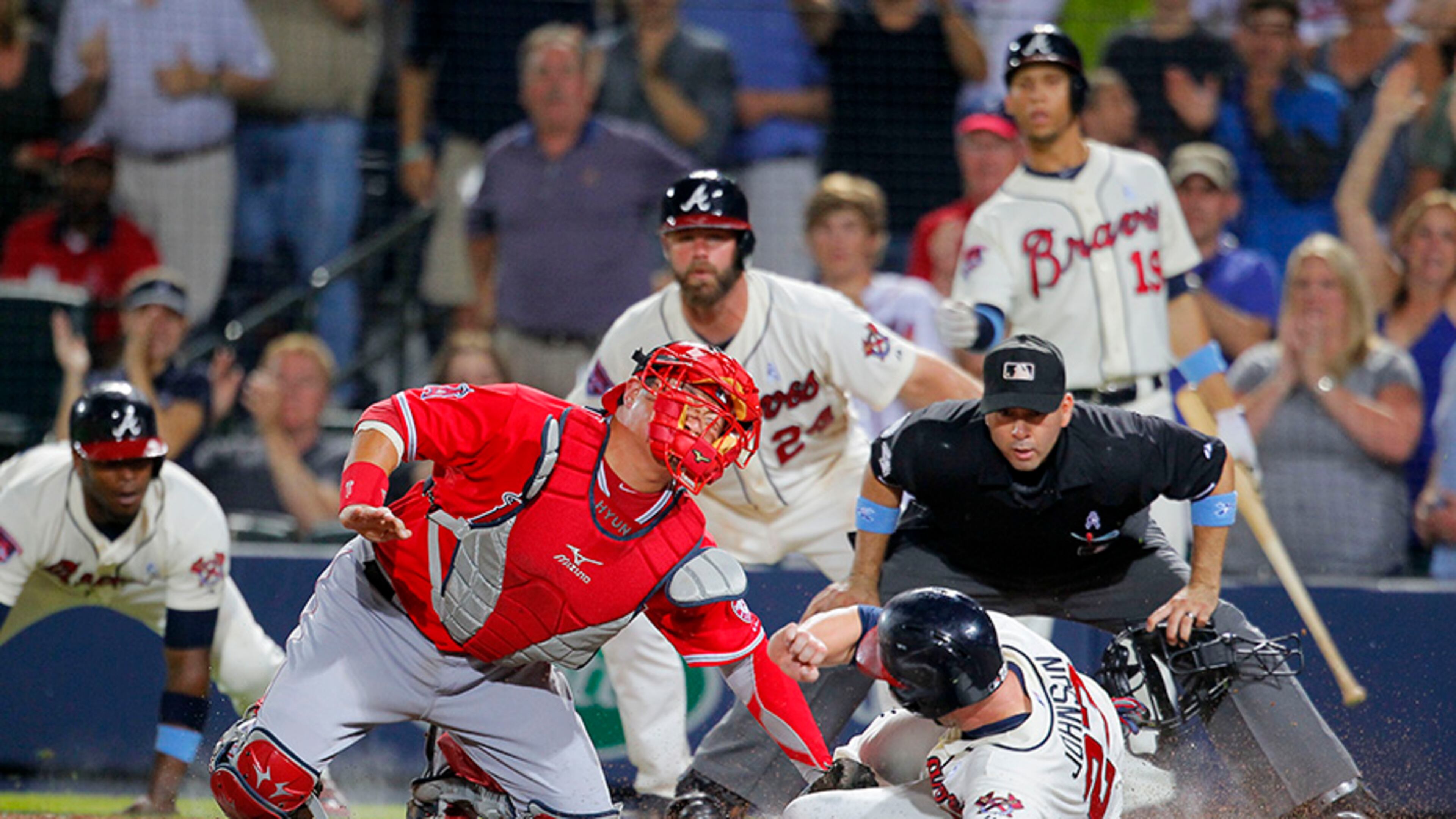 Los Angeles Angels catcher Hank Conger (16) tags out Braves third baseman Chris Johnson (23) at the plate after Tommy La Stella brings in two runs in the sixth inning Sunday at Turner Field
