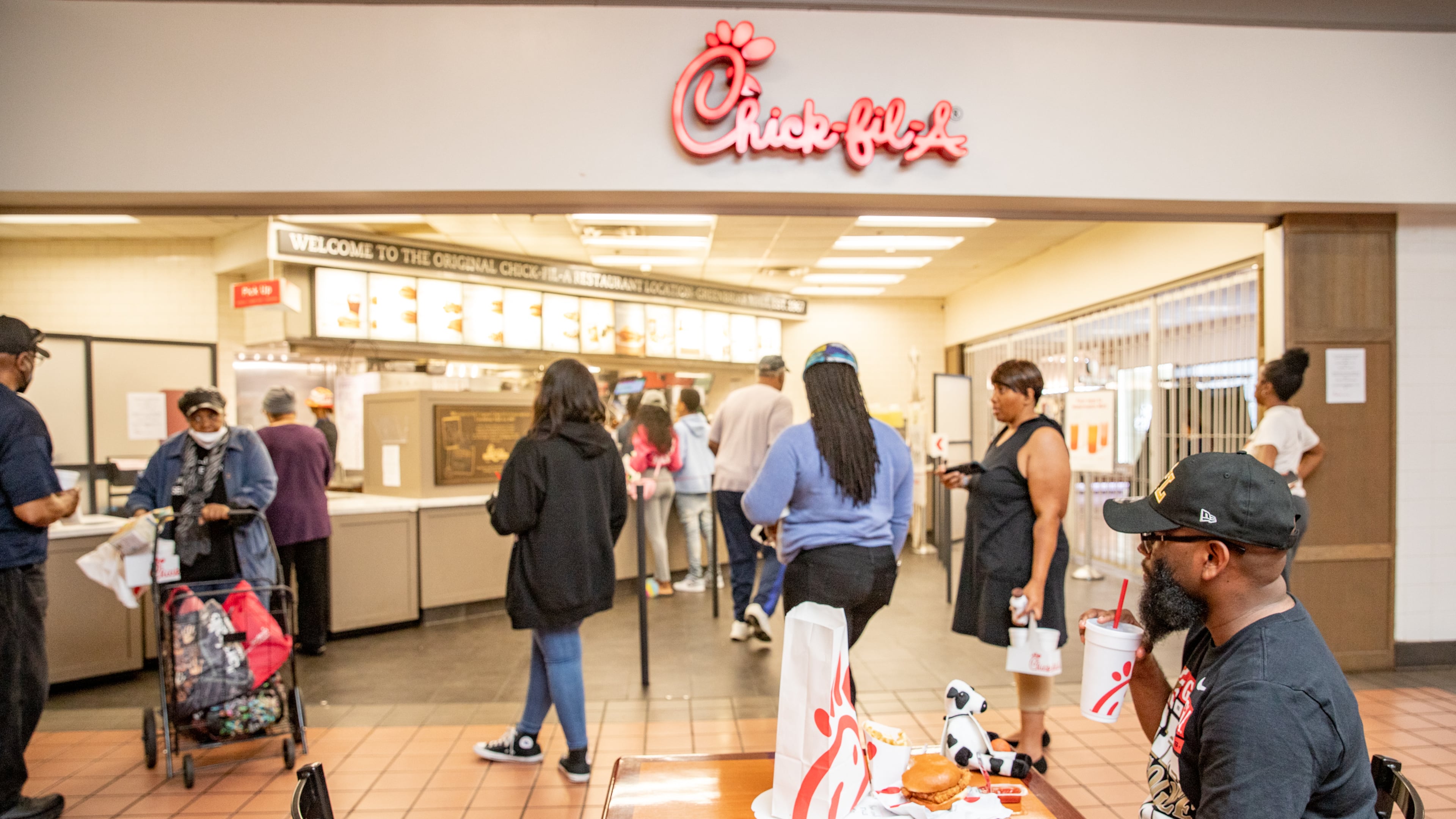 The first Chick-fil-A opened in 1967 in Greenbriar Mall and is now closing on Saturday, May 20, 2023. Patrons from all over the South, including Marquise Drayton, seated, of Clemson, SC, came to buy one last chicken sandwich from the mall's food court. Several people remember middle school and friends gathering at the restaurant and some were at the establishment on the first day it opened. (Jenni Girtman for The Atlanta Journal-Constitution)