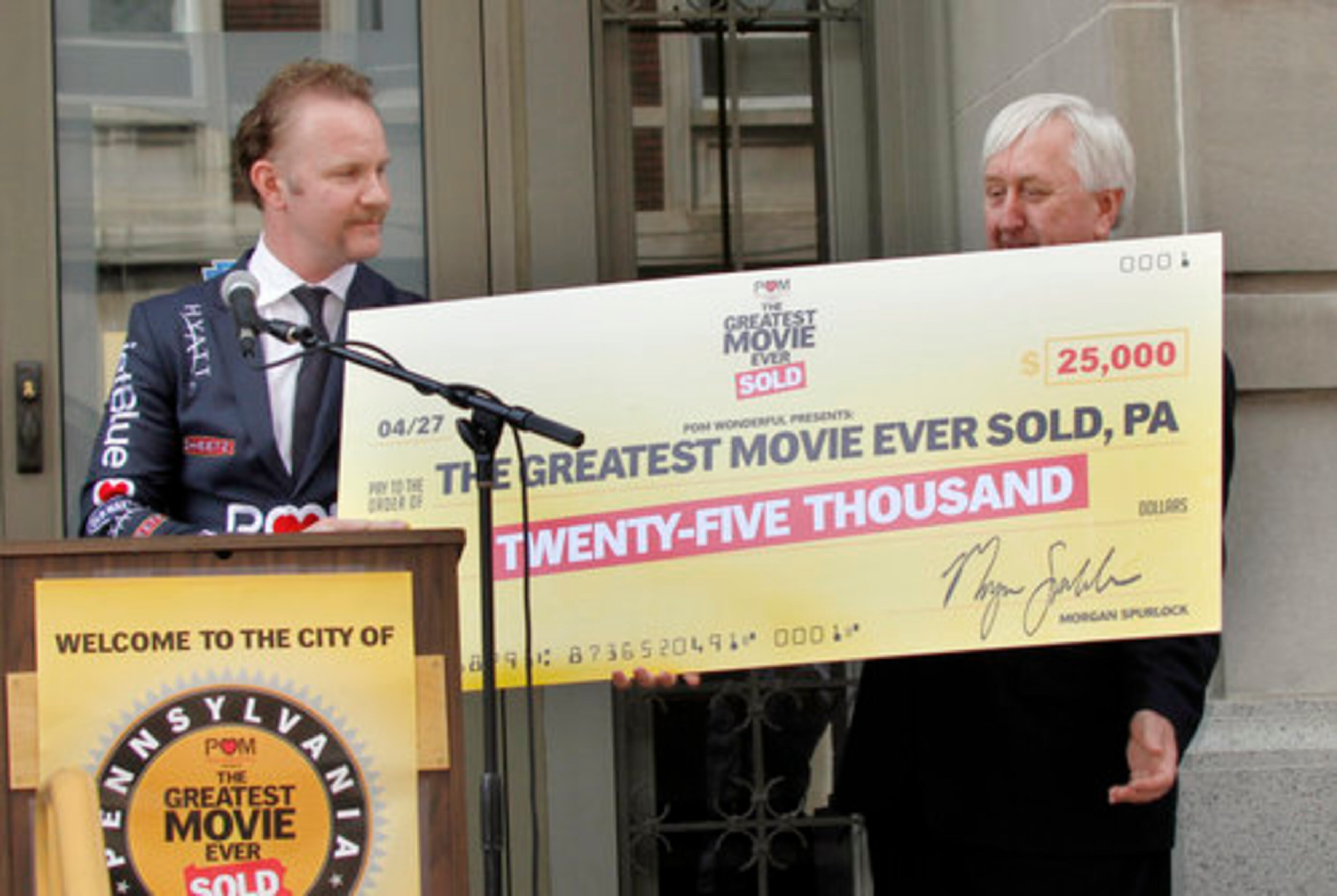 Spurlock, left, hands a ceremonial check to Altoona Mayor William Schirf. "We live in a place and a time when it seems like everything is brought to you by some sponsor," Spurlock told The Associated Press. "It starts to become this question of, 'Where does it end?'"