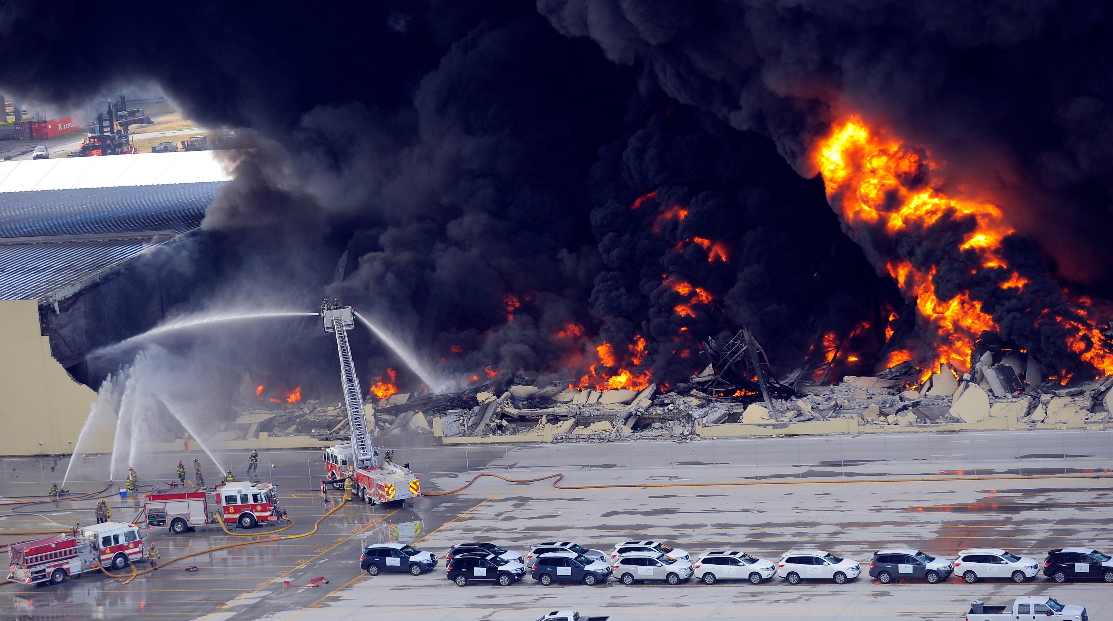 Savannah firefighters use a ladder truck to battle a blaze in a warehouse at the Georgia Ports Authority Ocean Terminal, Saturday, Feb. 8, 2014, in Savannah, Ga. Burning rubber from the fire at the Port of Savannah sent up a towering column of black smoke that could be seen from miles away. The cause of the fire wasn't immediately known, but all port workers were accounted for and unharmed. (AP Photo/Stephen B. Morton)