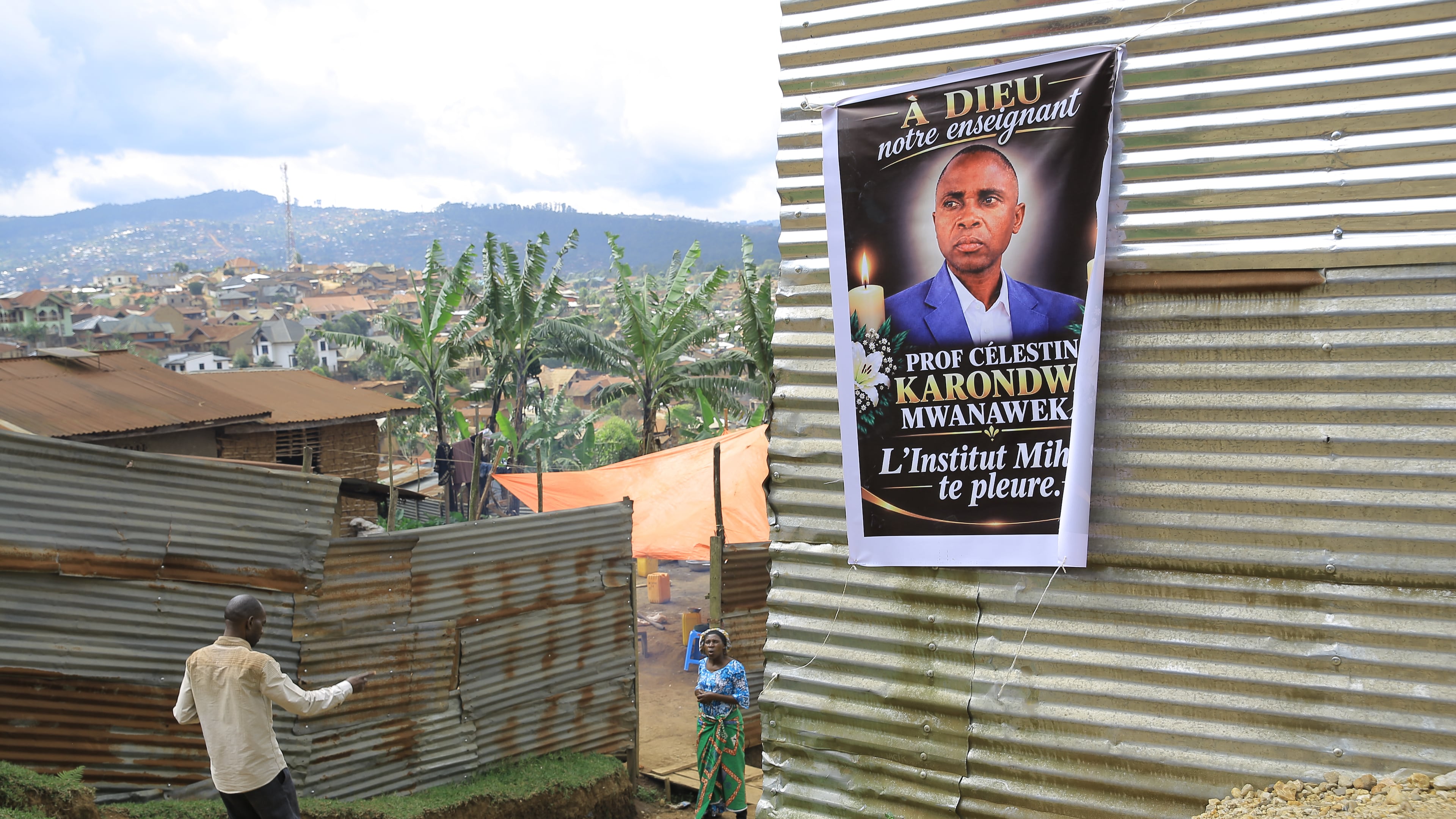 People walk past a banner with a photo of Marie-Célestin Karondwa, a local official who was beaten to death after publicly defending the government's response to Ebola, in Butembo, Congo, Wednesday, Sept. 30, 2026. (AP Photo/Sebastien Kitsa Musayi)