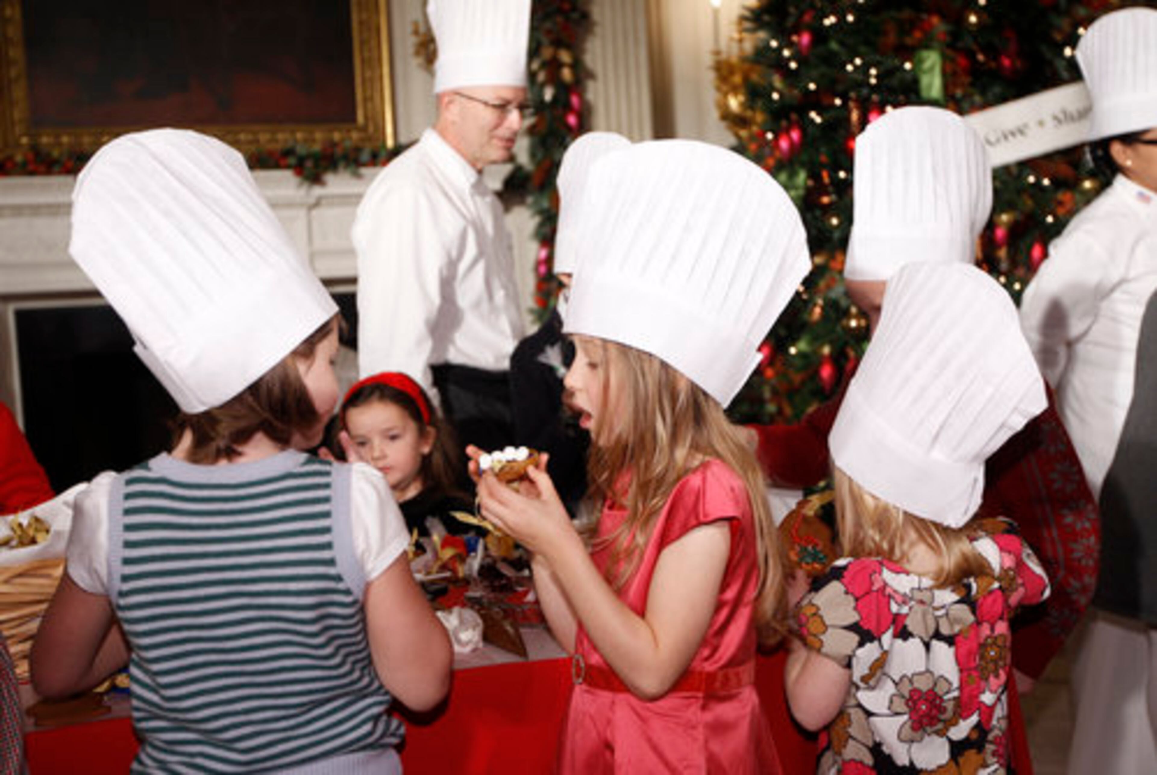 Children from military families decorate and sample holiday cookies as White House pastry chef Bill Yosses is seen at rear center in the State Dining Room.