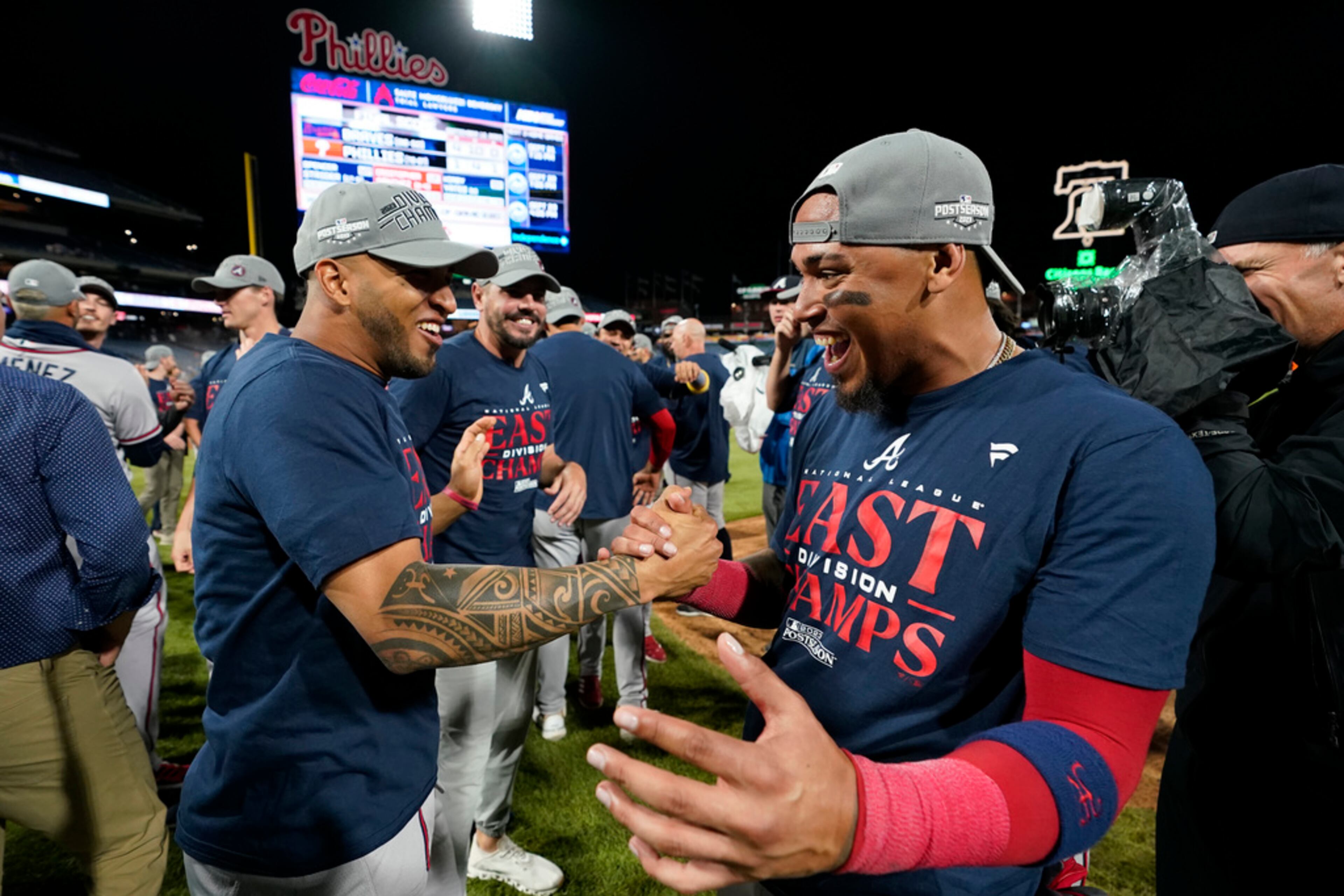Atlanta Braves' Eddie Rosario, left, and Orlando Arcia celebrate after clinching their sixth consecutive NL East title by defeating the Philadelphia Phillies in a baseball game, Wednesday, Sept. 13, 2023, in Philadelphia. (AP Photo/Matt Slocum)