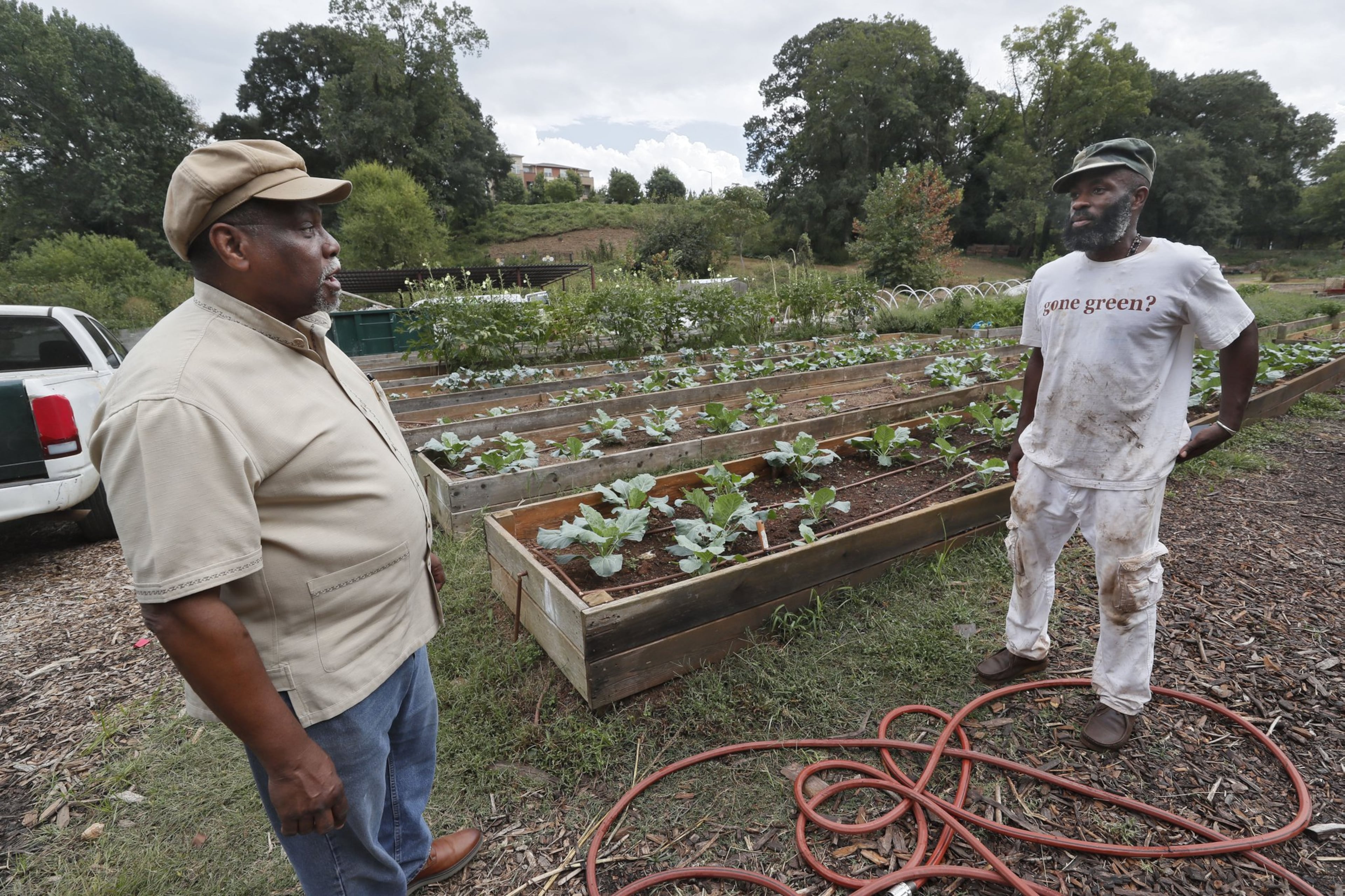 On a visit to the Truly Living Well urban farm in Atlanta, K. Rashid Nuri (left) talks with Ras Kofi, who was working in the garden. Nuri is known as the elder statesman of Atlanta’s urban gardening.