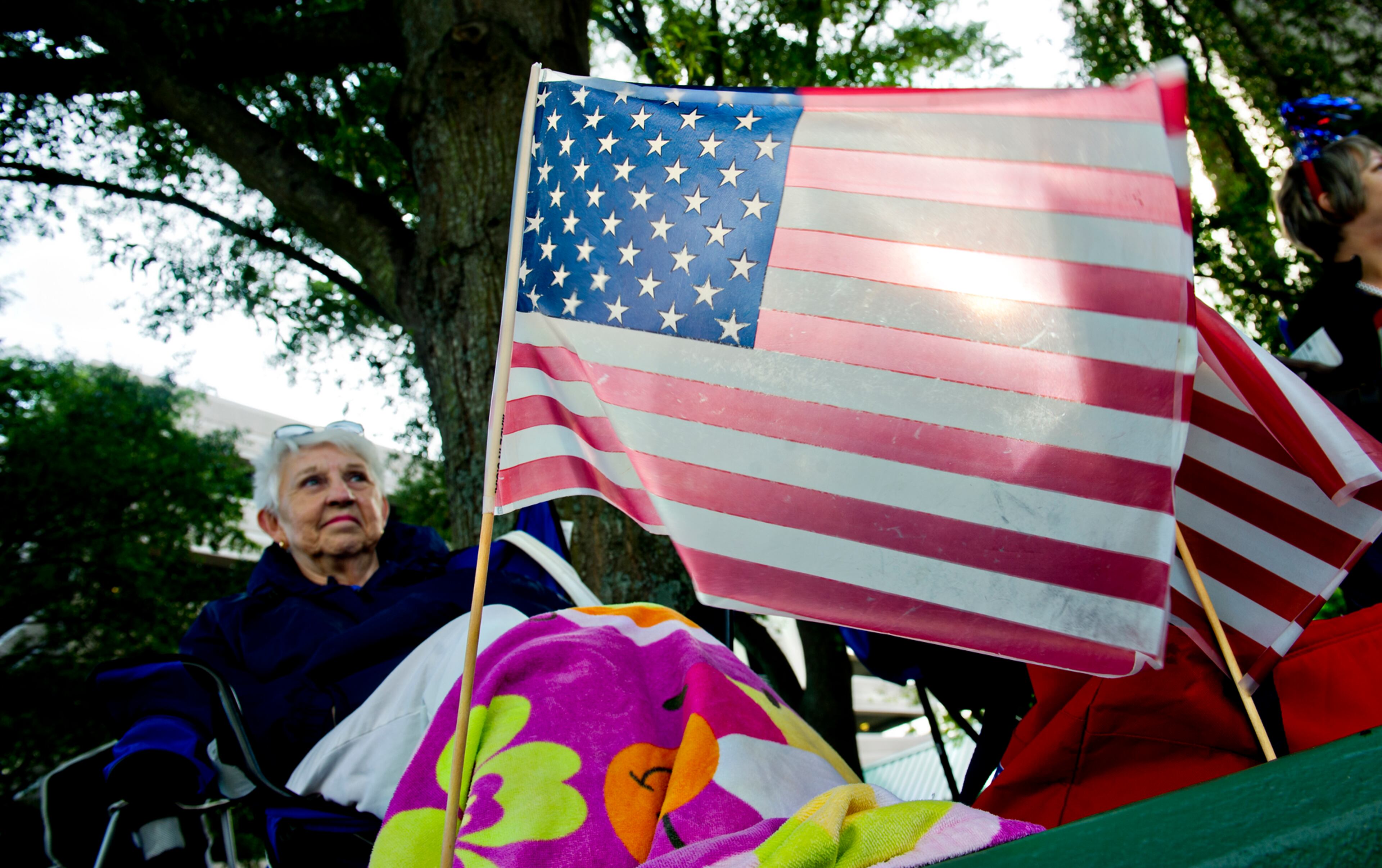 July 4, 2014 Marietta - An American flag glows in the morning light as Jo Bagwell (left) waits for the start of the Marietta Freedom Parade on Friday, July 4, 2014. The parade was part of Marietta's Fourth in the Park celebration which included free live concerts, museum tours, an arts and crafts show, food, carnival games and a fireworks finale. The Marietta Freedom Parade included 110 entries, 2,000 participants and an estimated 30,000 spectators. JONATHAN PHILLIPS / SPECIAL