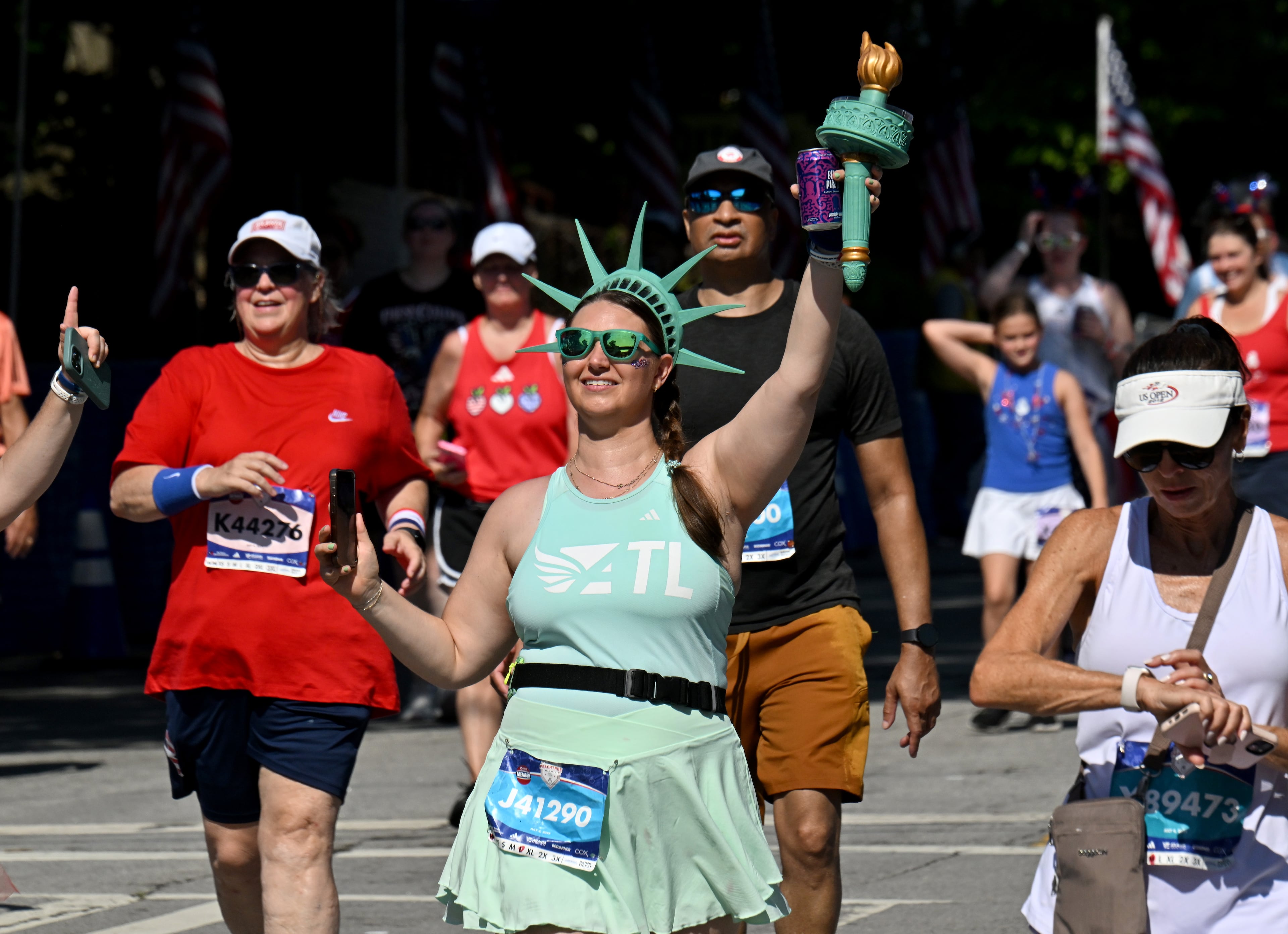 Runners celebrate as they cross the finish line of the 56th running of the Atlanta Journal-Constitution Peachtree Road Race in Atlanta on Friday, July 4, 2025. (Hyosub Shin / AJC)