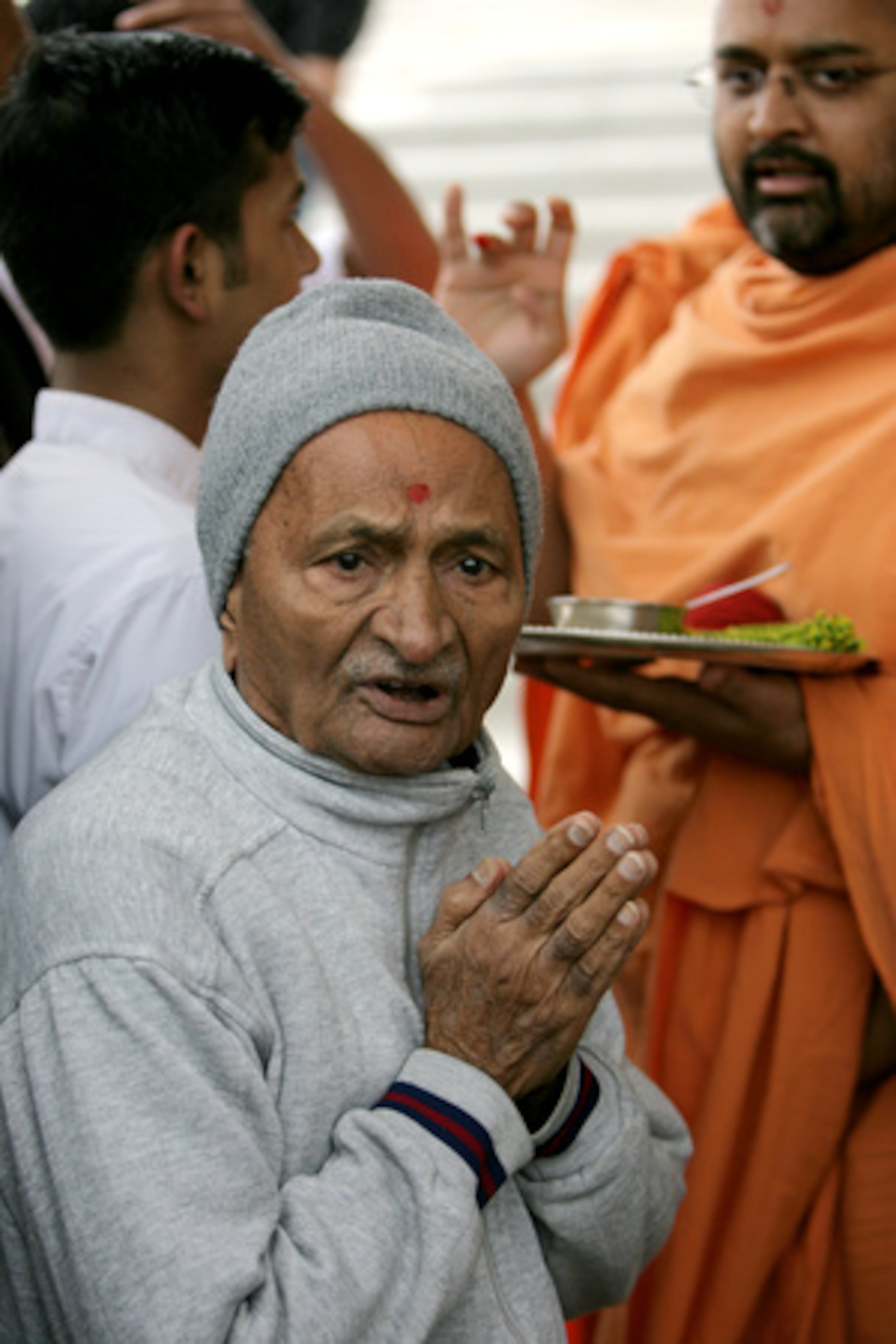 Mangaldas Patel prays as Sadhu Amrutnandan Swami (right) performs a sacred ceremony to open the book store and gift shop during the kite festival.