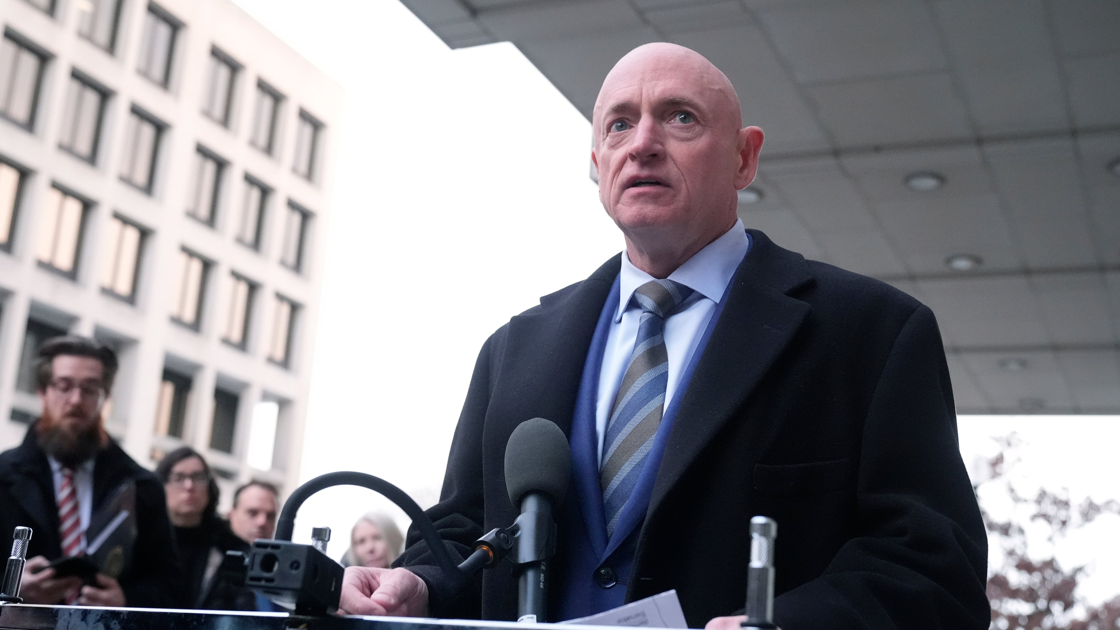 Sen. Mark Kelly, D-Ariz.,speaks to reporters outside of federal court in Washington, Tuesday, Feb. 3, 2026. (AP Photo/Mark Schiefelbein)