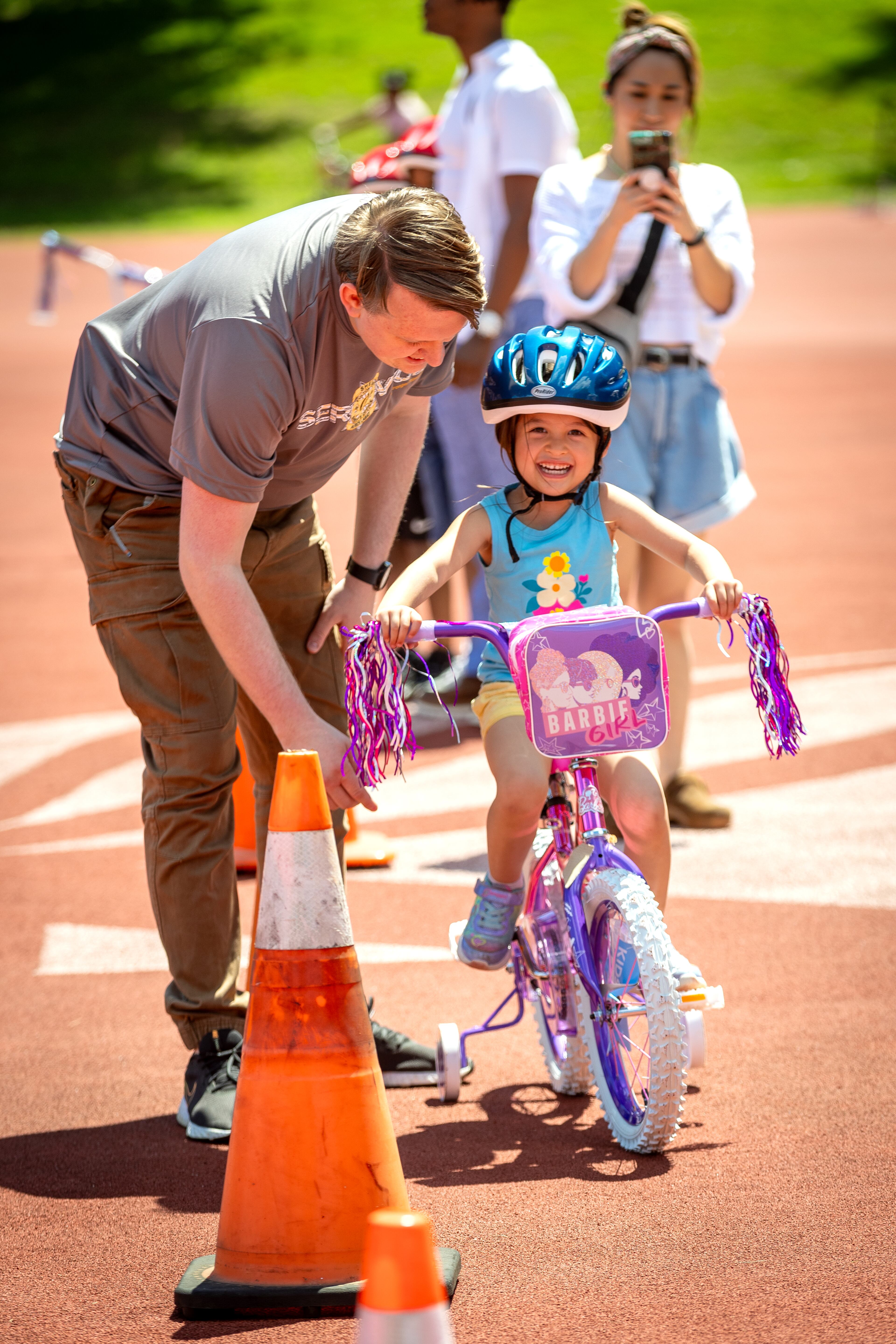 Joseph Memmelaar helps his daughter Claire, 2, learn to ride a bike during the Fulton County Sheriff's Office bike-a-thon at Cheney Stadium in Atlanta on Saturday, May 11, 2024. (Steve Schaefer / AJC)