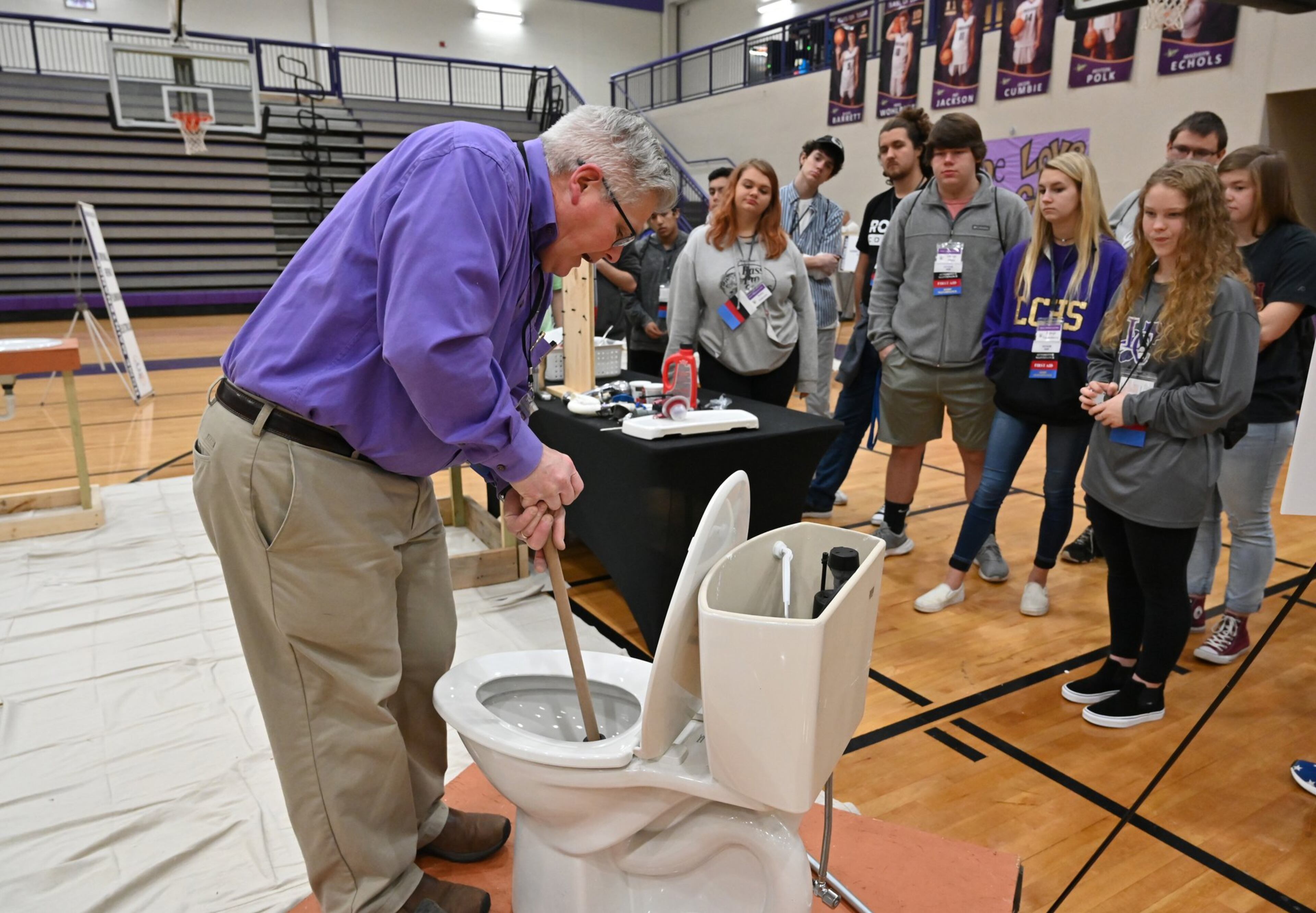 Instructor Jeff Bearinger (foreground) demonstrates how to plunge a toilet during the second annual Senior Adulting Day at Lumpkin County High School in Dahlonega on Friday, Jan. 24, 2020.