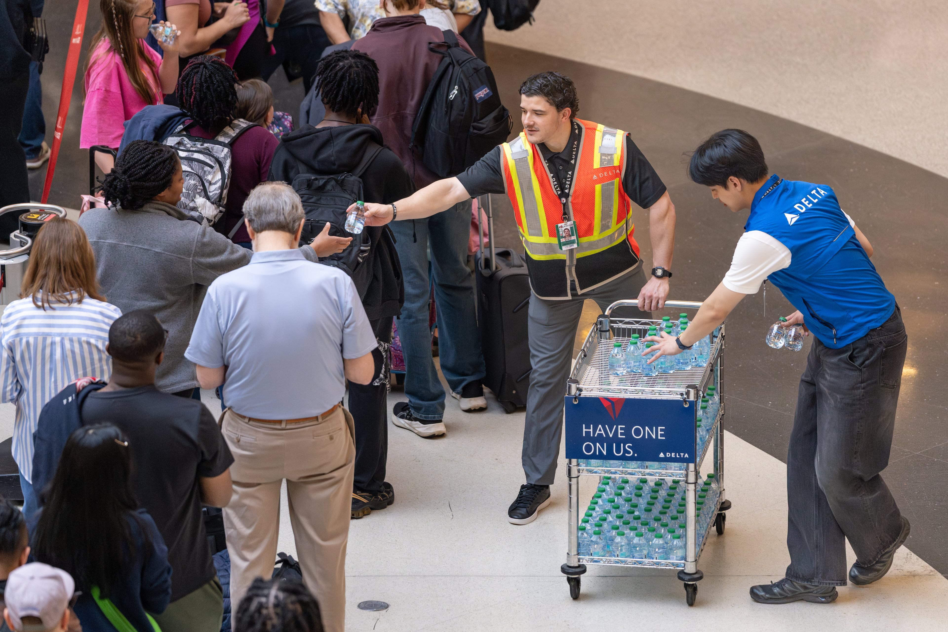A Delta employeee passes out bottled water to morning travelers waiting in multi-hour lines at Hartsfield-Jackson Atlanta International Airport amid the ongoing partial goverment shutdown. Monday, March 23, 2026 (Ben Hendren for the AJC)