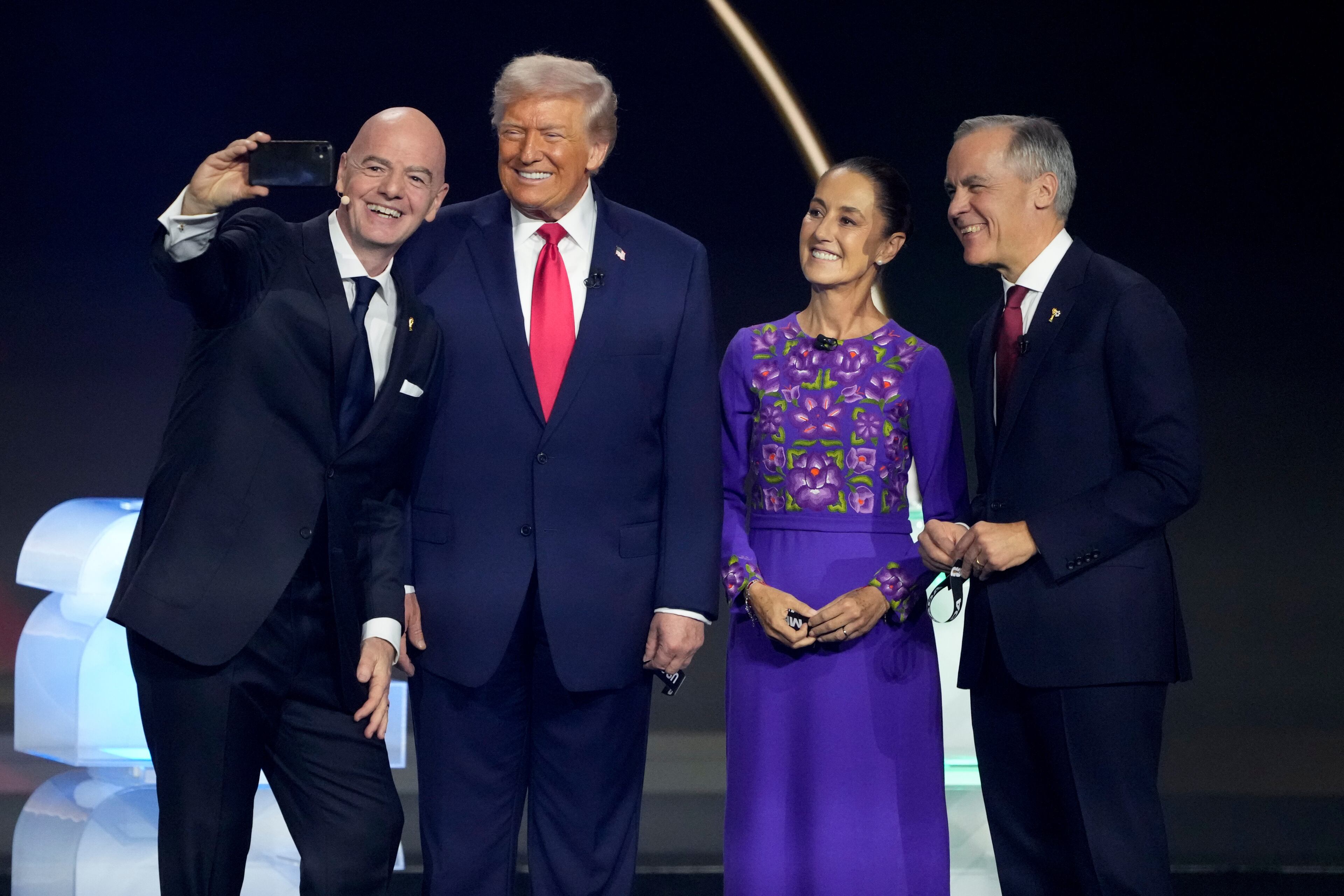 From left; FIFA President Gianni Infantino takes a selfie with President Donald Trump, Mexican President Claudia Sheinbaum, and Canadian Prime Minister Mark Carney during the draw for the 2026 soccer World Cup at the Kennedy Center in Washington, Friday, Dec. 5, 2025. (AP Photo/Chris Carlson)