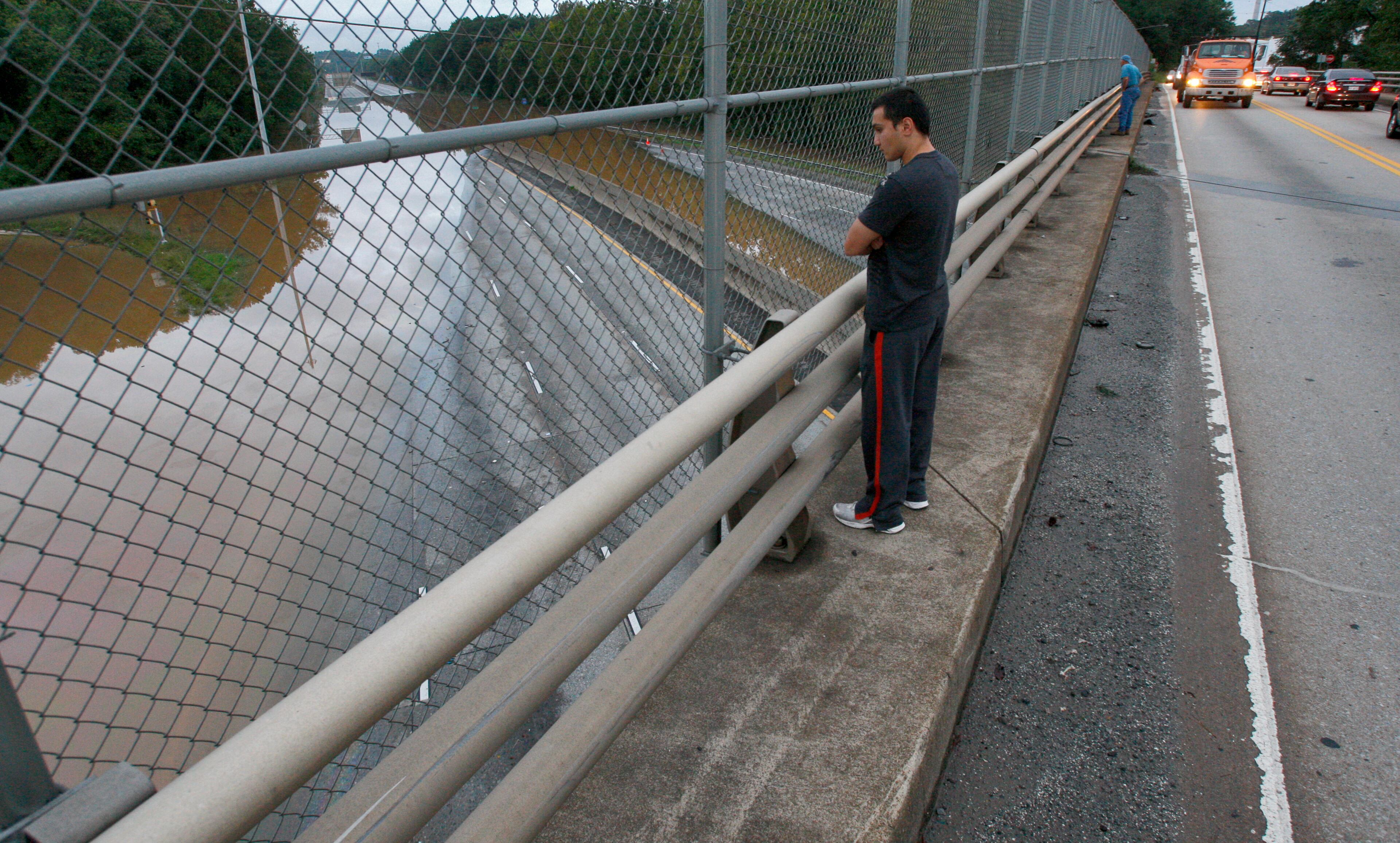 090921 - Cobb County - Frank Ubay was on the way home to Nashville from Florida when he heard about the flooding in Atlanta and took a look at the flooded I-285 from the Bolton Road overpass Tuesday. The flooding continued Tuesday September 22, 2009 in the Atlanta metro area as I-285 at the Bolton Road overpass - north by several hundred yards was flooded over both sides of the interstate. Georgia Department of Transportation crews closed 11 bridges and a number of state-controlled roads and highways after Monday's flooding. DOT officials recommended that commuters who didn't need to travel remain home. "If someone is in an area that is experiencing flooding over the past few days, it may be a challenge to commute," spokeswoman Crystal Paulk-Buchanan. "The challenge that people are going to have are county roads and city roads." Among state thoroughfares, I-285 northbound at Hollowell Parkway and southbound at Cobb Parkway in Cobb County remained closed, because water from the Chattahoochee River was cresting the bridges. Flooding on Sweetwater Creek closed the I-20 eastbound lane between Lee and Thornton roads. The bridge will remain closed until the water recedes, and detours are in place. DOT also closed I-575 just at Highway 92 near the Cobb-Cherokee county line for flooding. DOT officials expect to open the three closed road sometime Tuesday, but Paulk-Buchanan said, in particular, bridges will remain closed so long as water is touching the underside of the bridges. John Spink, jspink@ajc.com