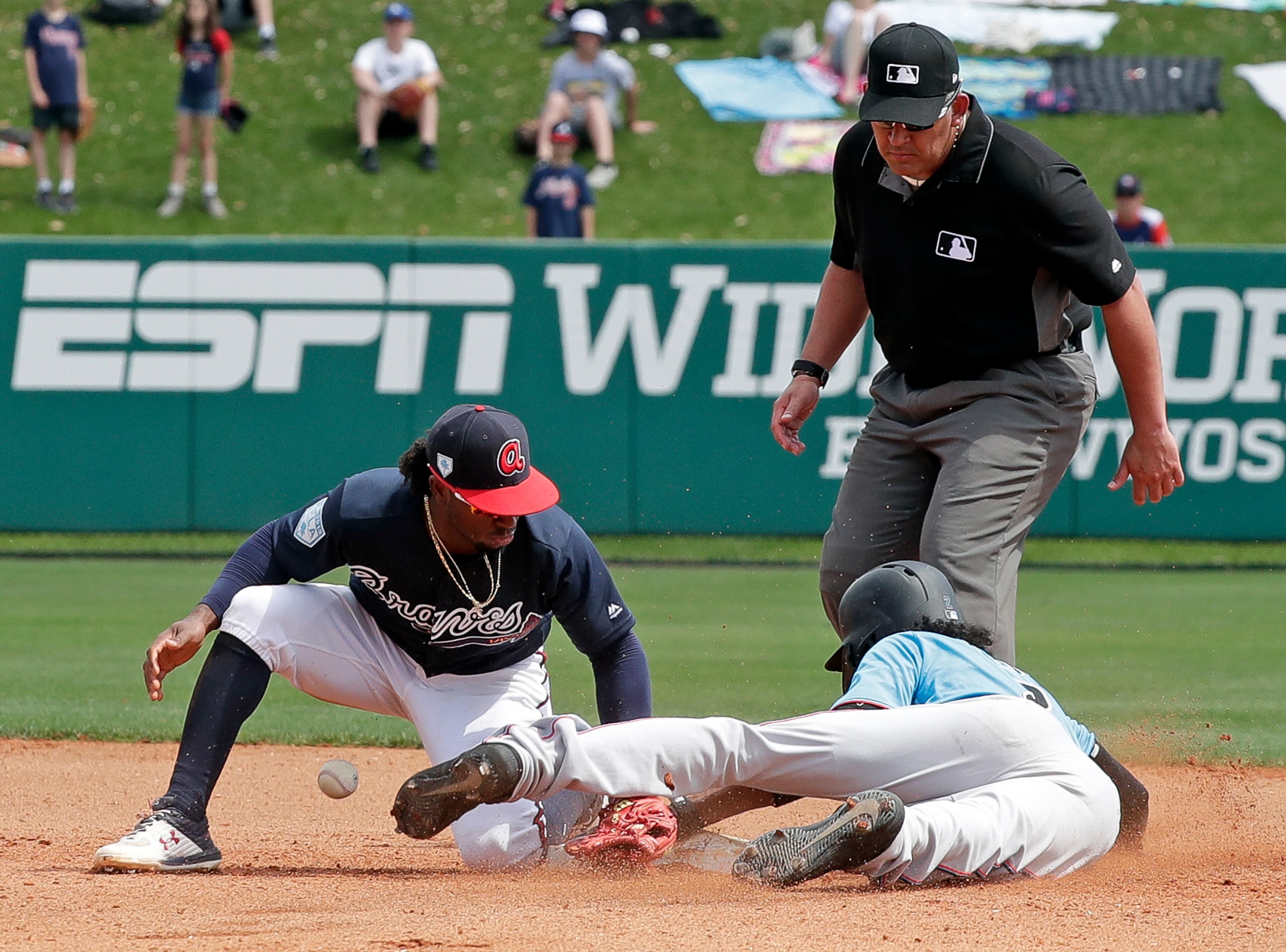 Atlanta Braves second baseman Ozzie Albies, left, drops the ball trying to tag Miami Marlins' Yadiel Rivera, lower right, stealing second base, in the fourth inning of a spring baseball exhibition game, Friday, March 15, 2019, in Kissimmee, Fla. (AP Photo/John Raoux)