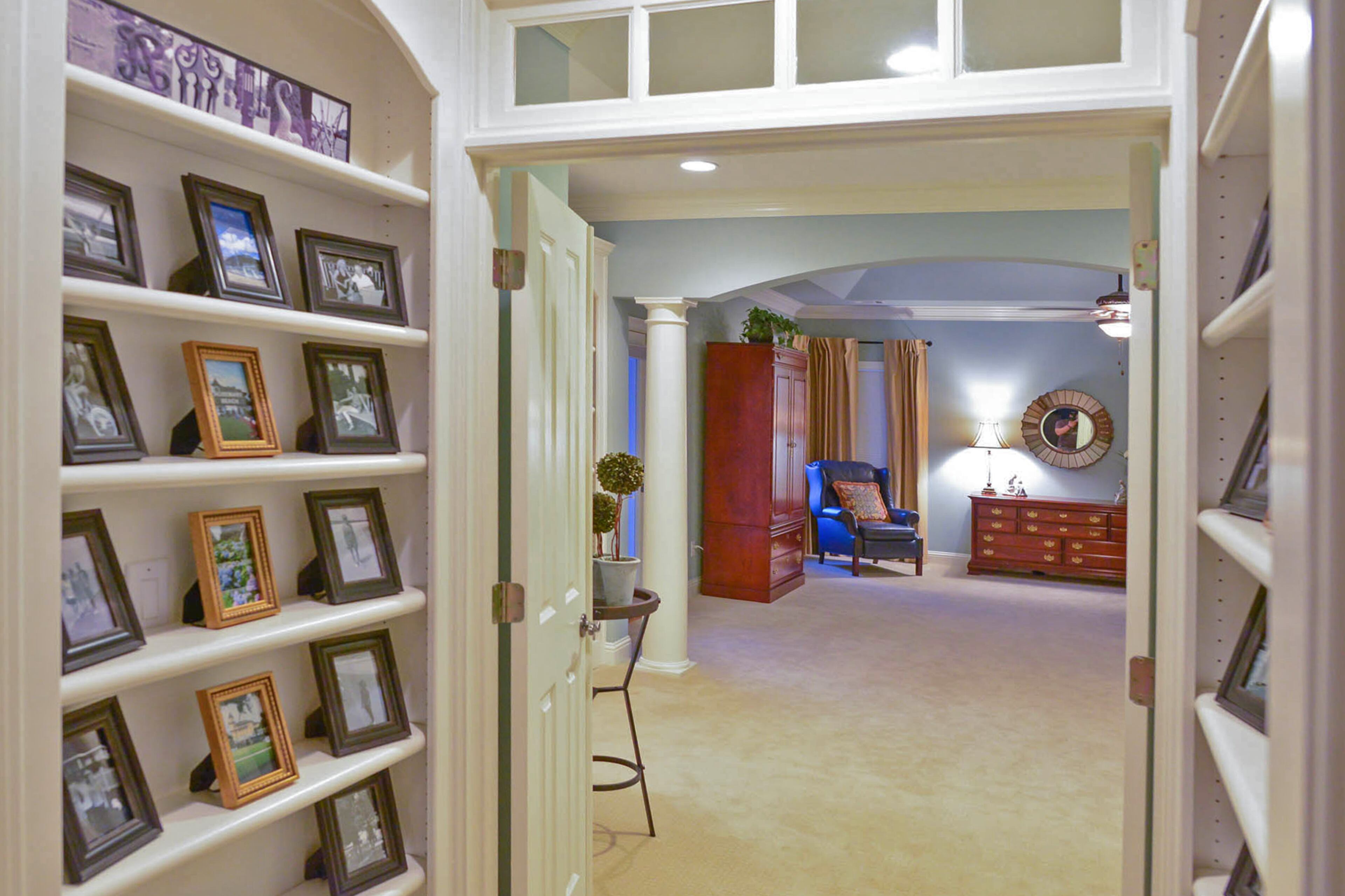 Built-in shelving on both sides of a hallway leading to the master bedroom is filled with photos from family trips.