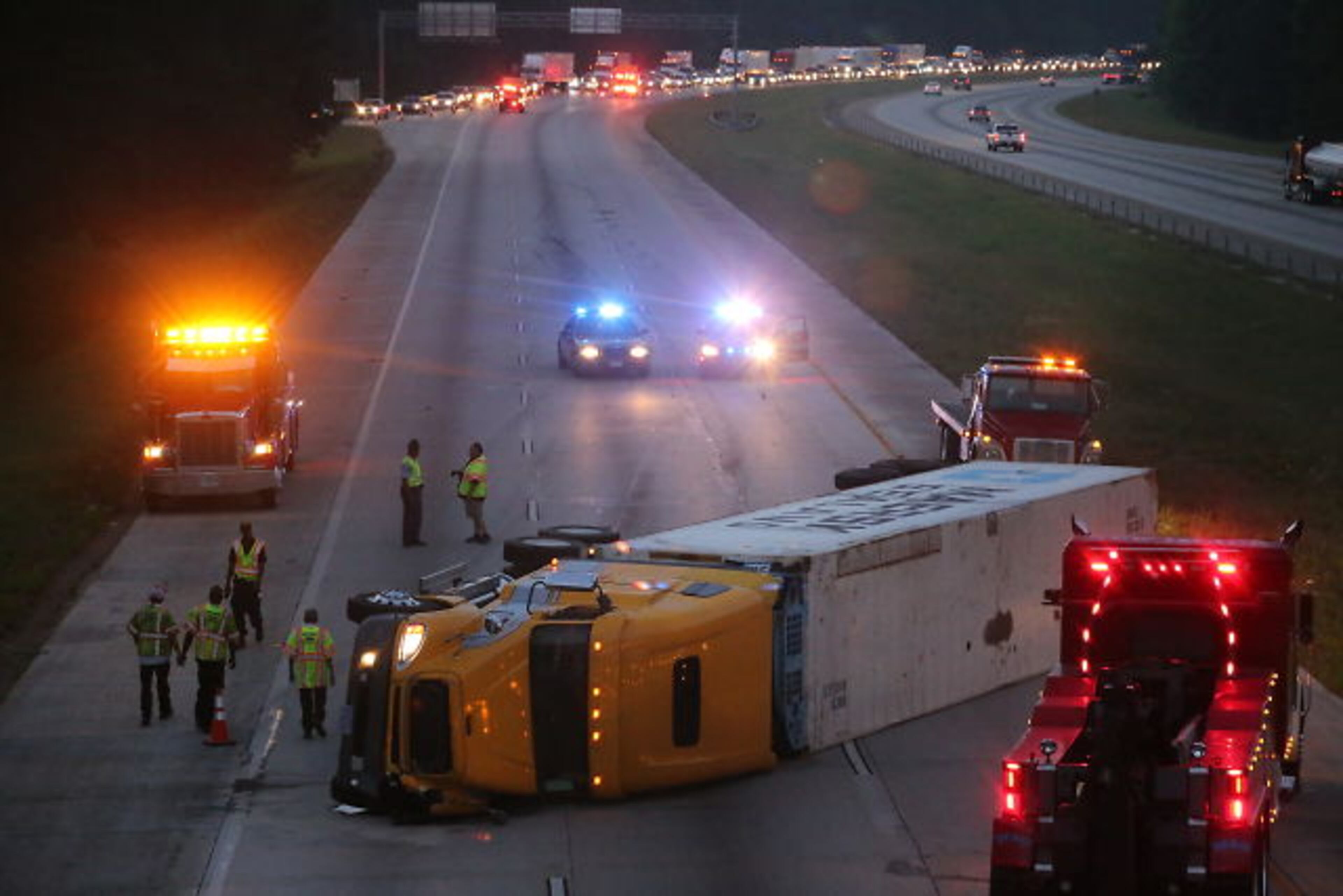 An overturned tractor-trailer shut down I-675 northbound in Clayton County during the early stages of the June 19 morning commute. JOHN SPINK / JSpink@ajc.com