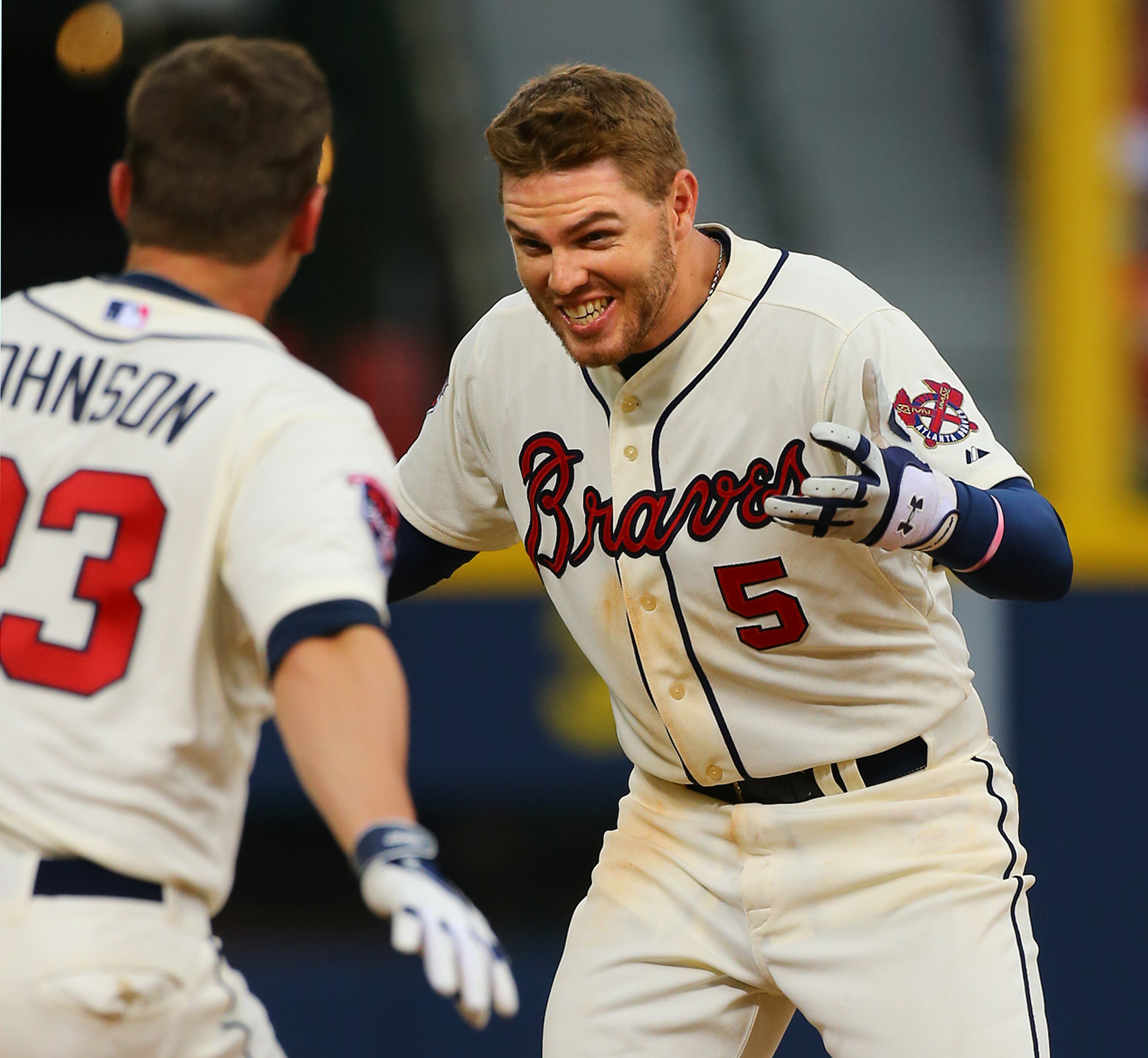 Chris Johnson (left) runs to celebrate with Braves Freddie Freeman after Freeman hit a game-winning RBI single in the 10th inning of their MLB baseball game on Sunday, April 27, 2014, in Atlanta. CURTIS COMPTON / CCOMPTON@AJC.COM