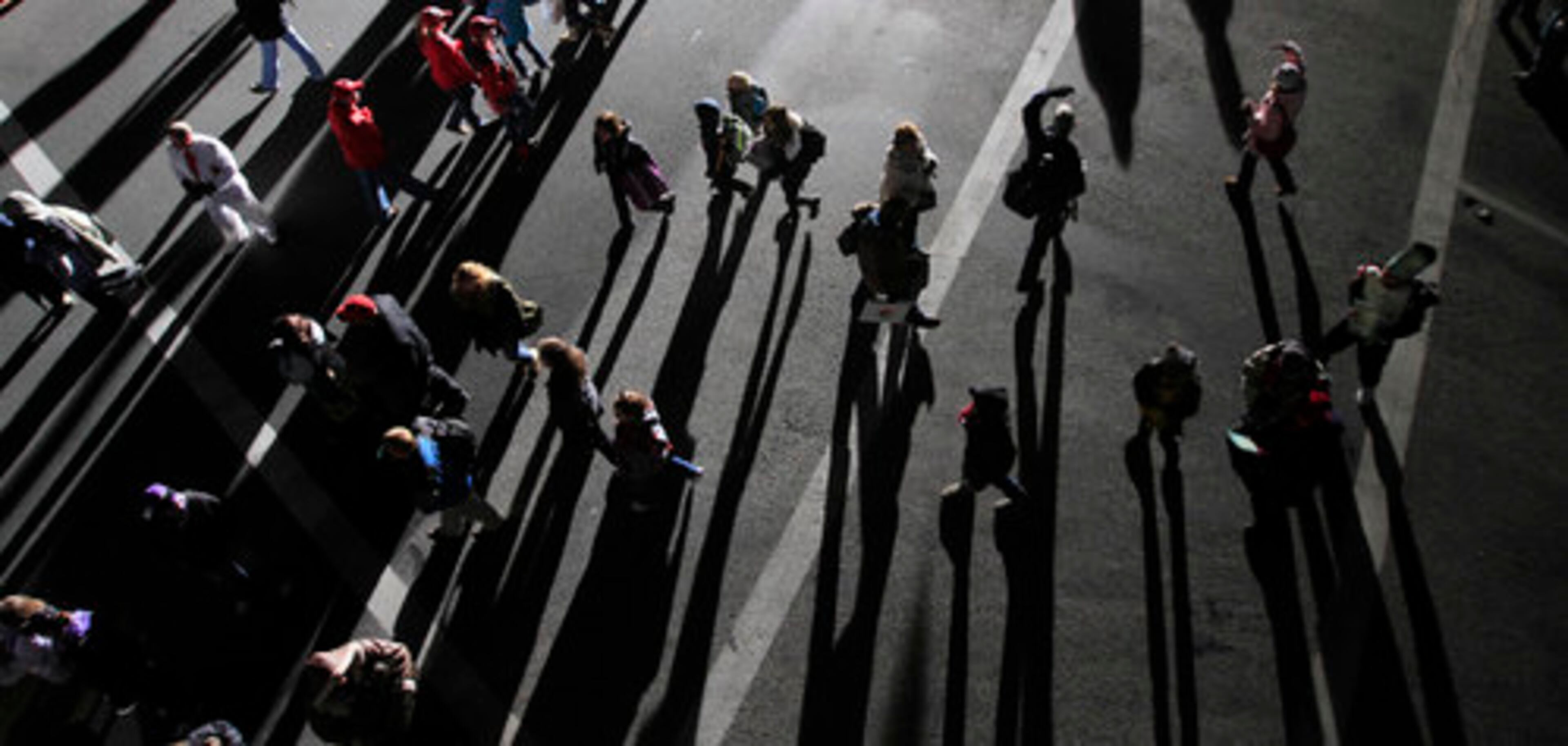 Spotlights cast long shadows on parade-goers as they find their seats prior to the start of the 122nd Rose Parade in Pasadena, Calif.
