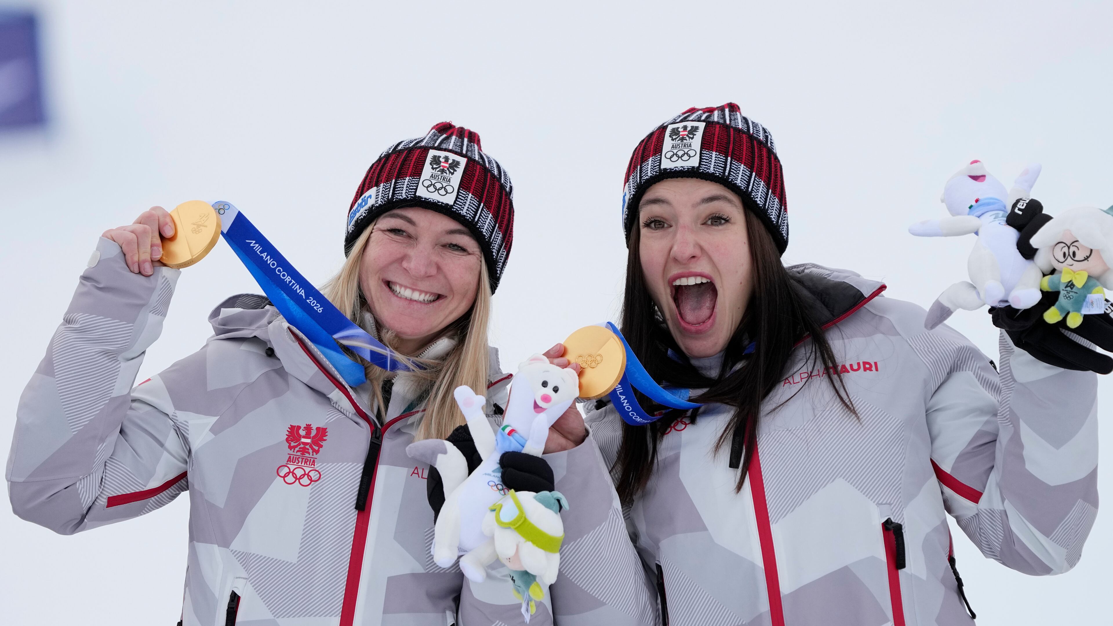 Austria's Ariane Raedler, left, and teammate Austria's Katharina Huber show their gold medals in an alpine ski, women's team combined race, at the 2026 Winter Olympics, in Cortina d'Ampezzo, Italy, Tuesday, Feb. 10, 2026. (AP Photo/Andy Wong)