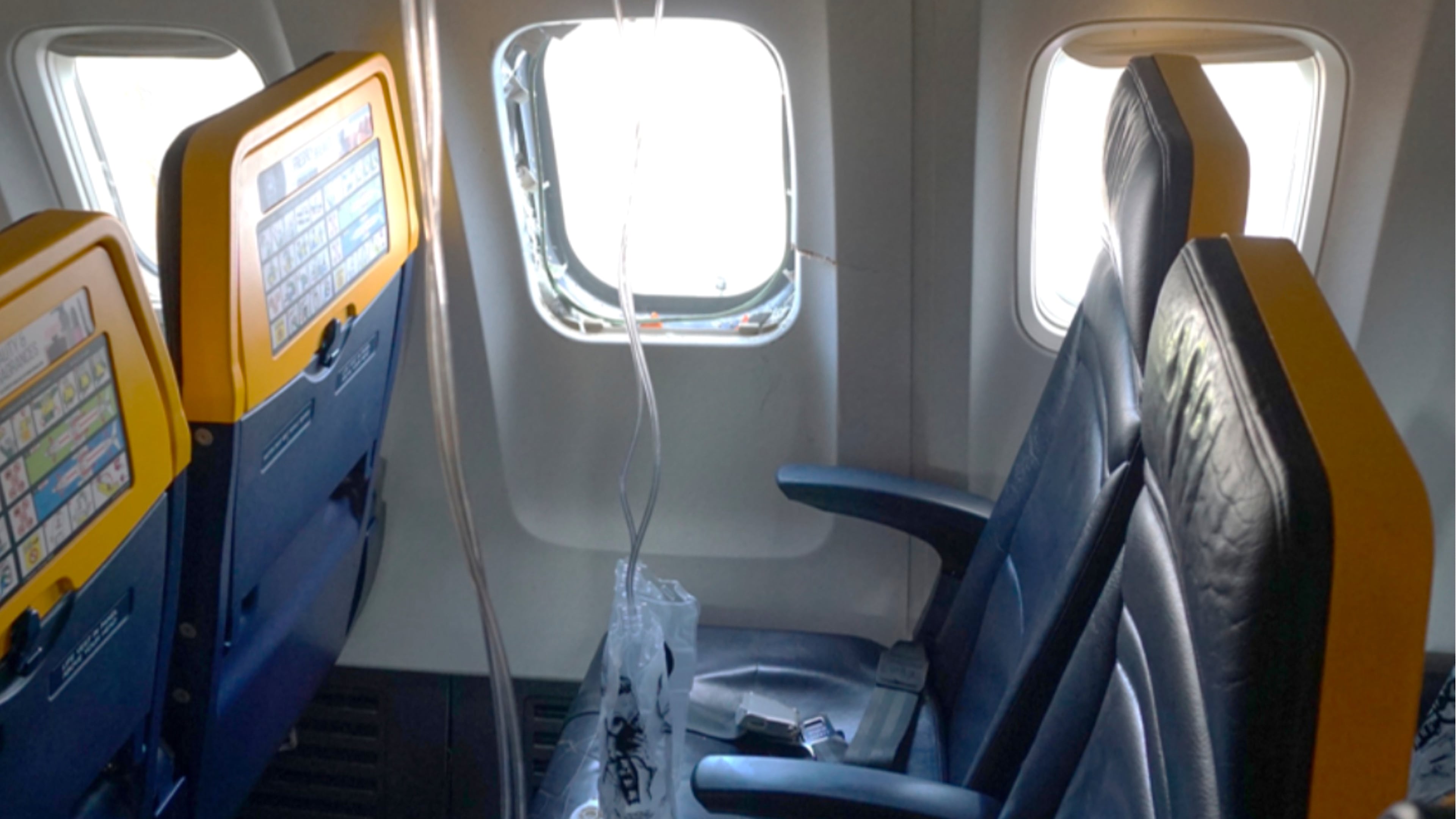 This undated photo provided by the National Transportation Safety Board on Thursday, Aug. 13, 2026, shows the shattered window on a Ryanair plane that was broken by a stray engine part shortly after takeoff, causing a man's head to be sucked into the hole. (National Transportation Safety Board via AP)