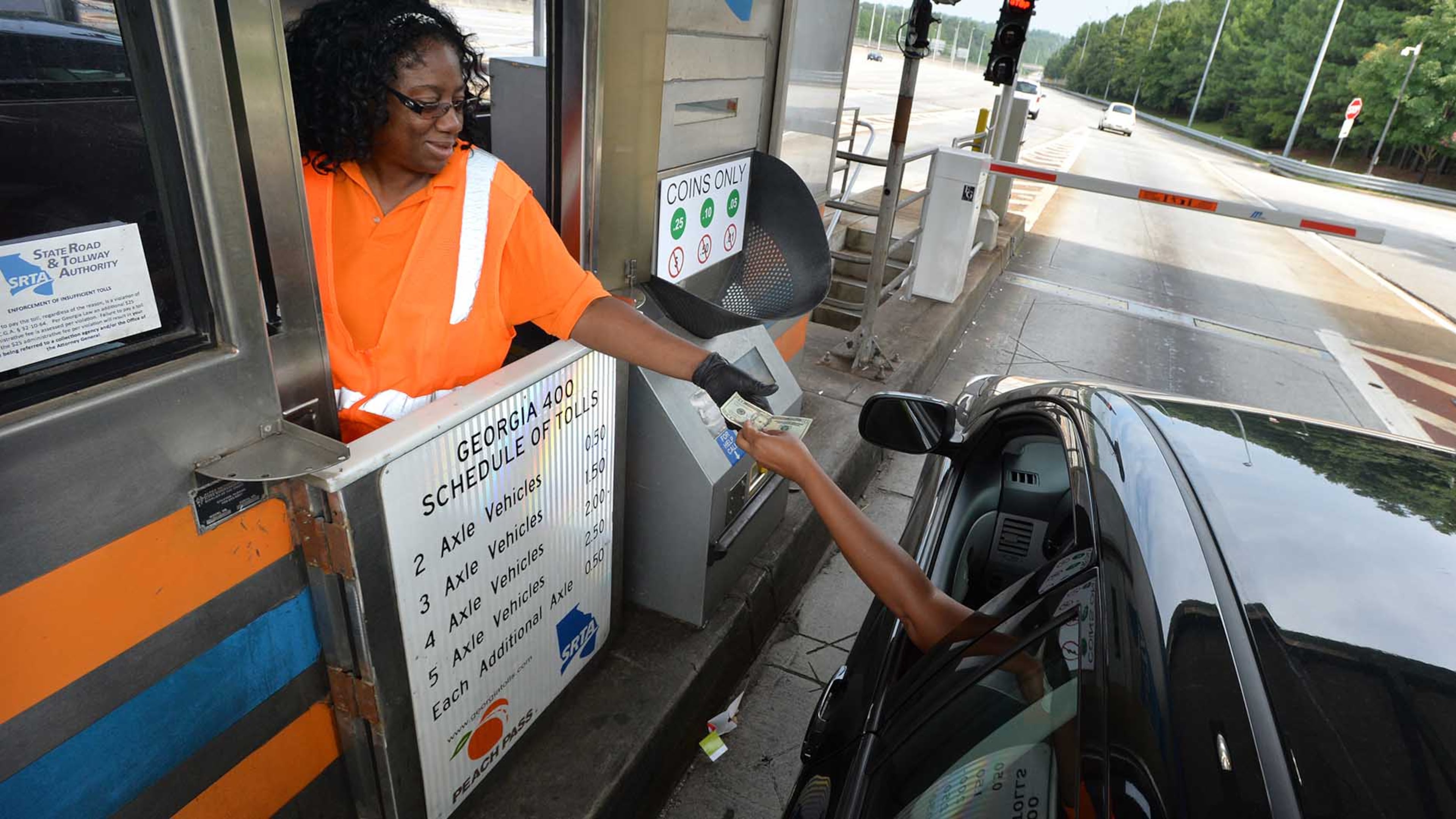 Fredricka Tyson-Holloway makes change for a customer passing through her toll booth on Ga. 400 Wednesay. Countless drivers over the years have "paid-it-forward" by donating their 50-cent change to the person waiting behind them in line at the GA 400 toll booth. But not any longer. The private company that has a contract to collect tolls for the state recently forbid toll workers from taking extra money from drivers.