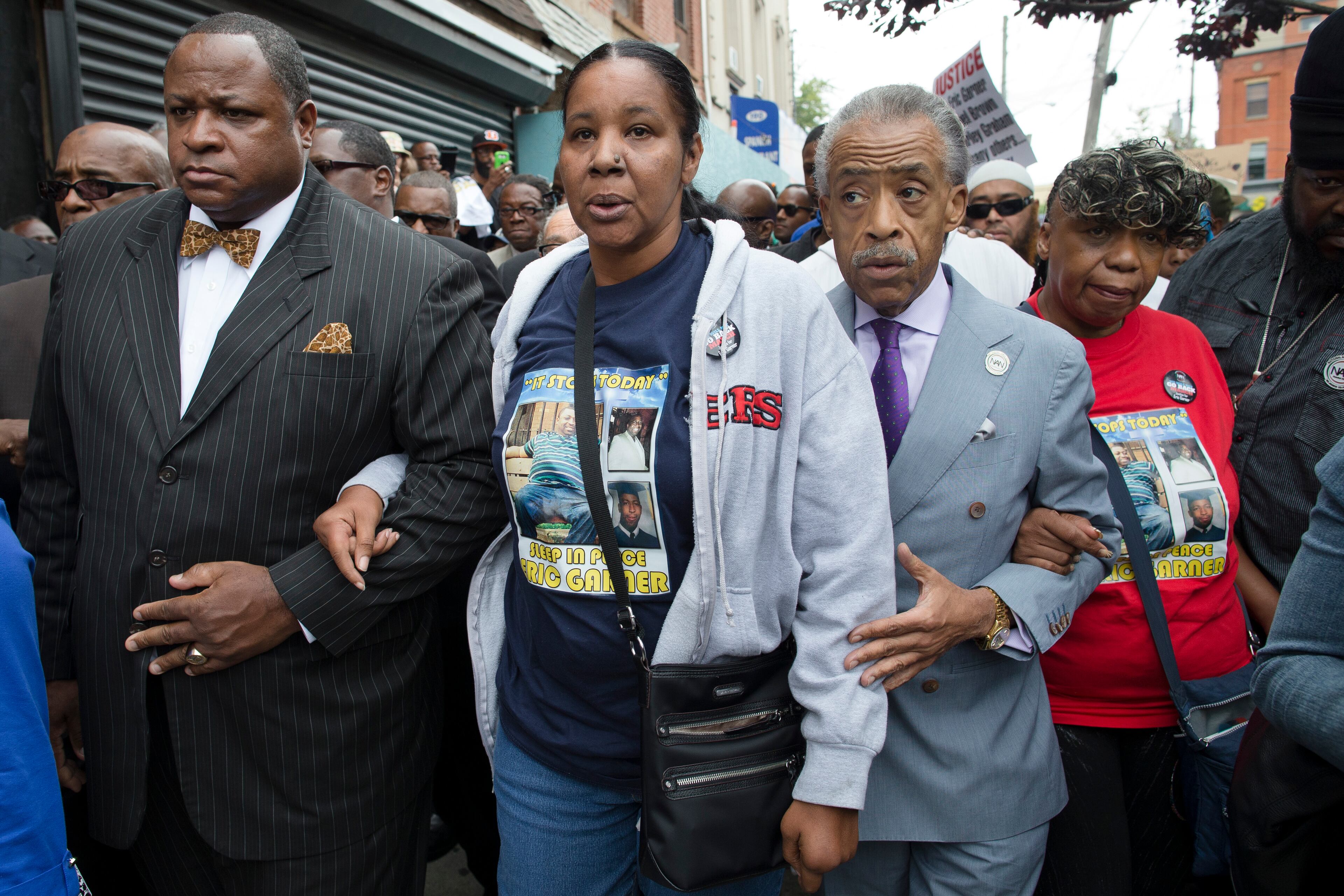 Esaw Garner, center, walks to the site where her husband Eric Garner dead alongside the Rev. Al Sharpton, center right, and her mother-in-law Gwen Carr, right, before march to protest of Eric Garners death, Saturday, Aug. 23, 2014, in the Staten Island borough of New York. The city medical examiner ruled that Eric Garner died as a result of a police chokehold during an attempted arrest. (AP Photo/John Minchillo)