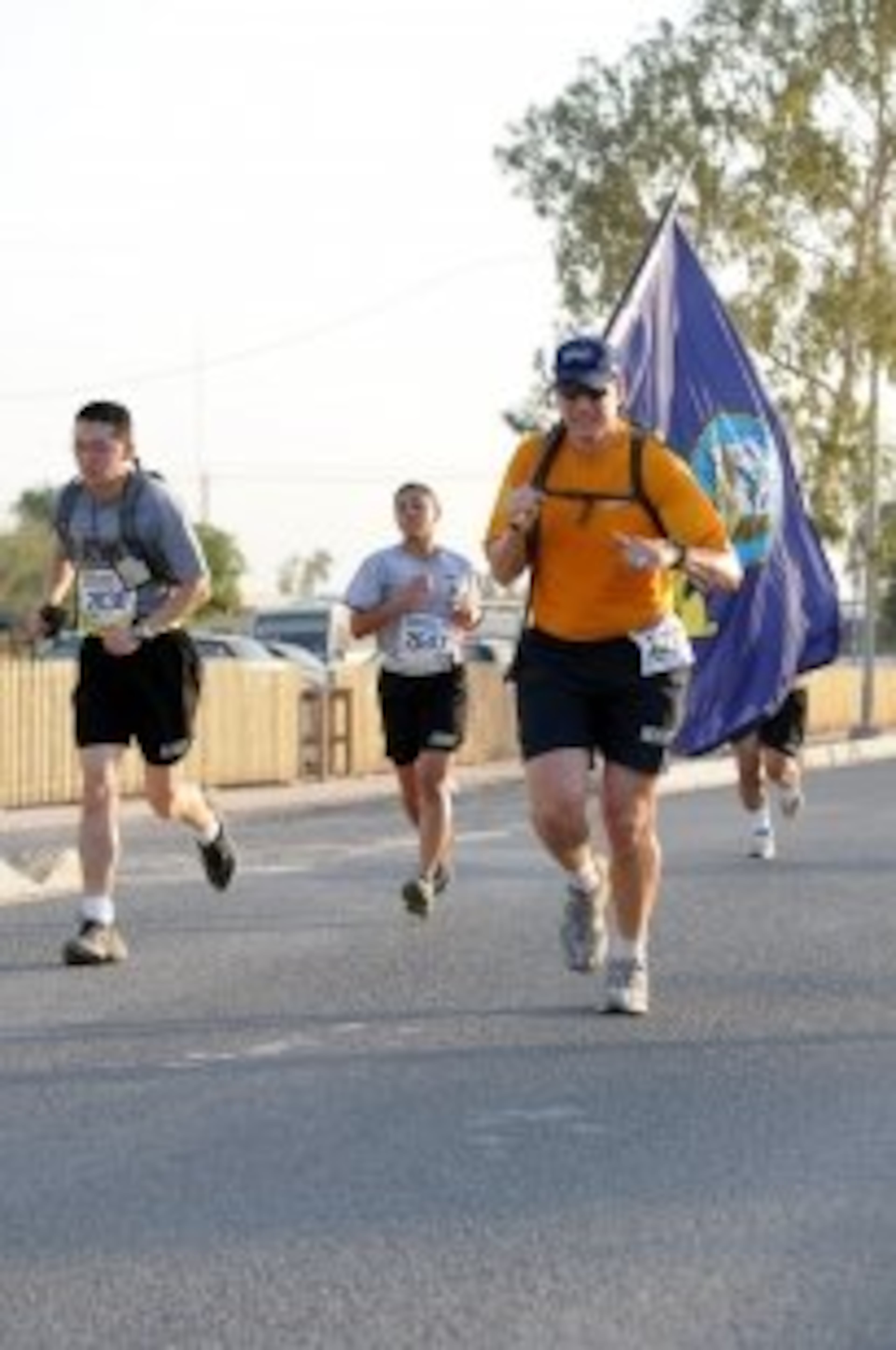 Navy Lt. Brandin Bignall, liaison officer assigned to the Expeditionary Logistics Group-Forward, runs with a Navy flag during the Atlanta Journal-Constitution Peachtree Road Race 10K shadow run held in Baghdad.