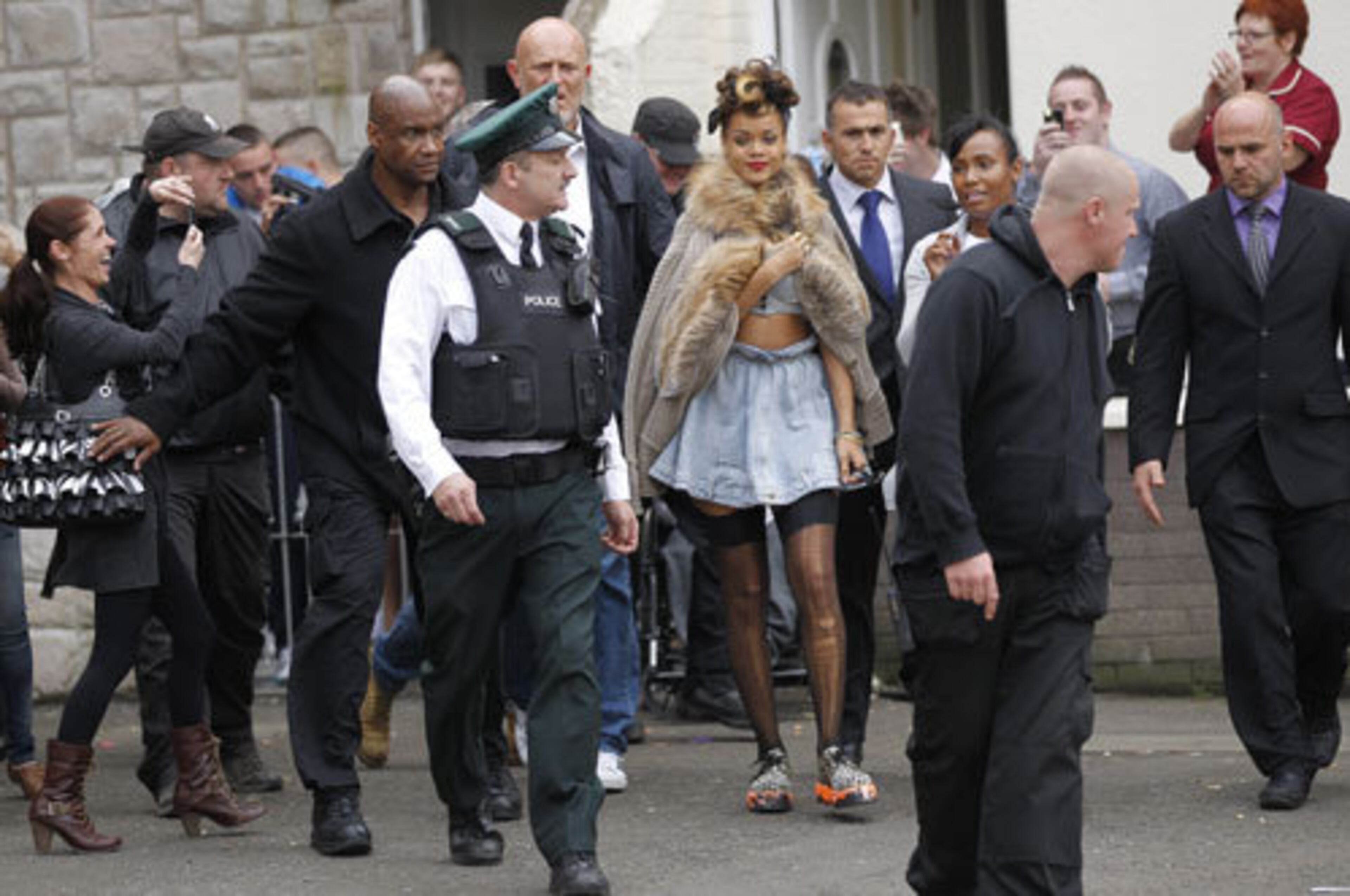 Members of the pop star's security team keep fans at bay as Rihanna arrives for her video shoot in Northern Ireland.