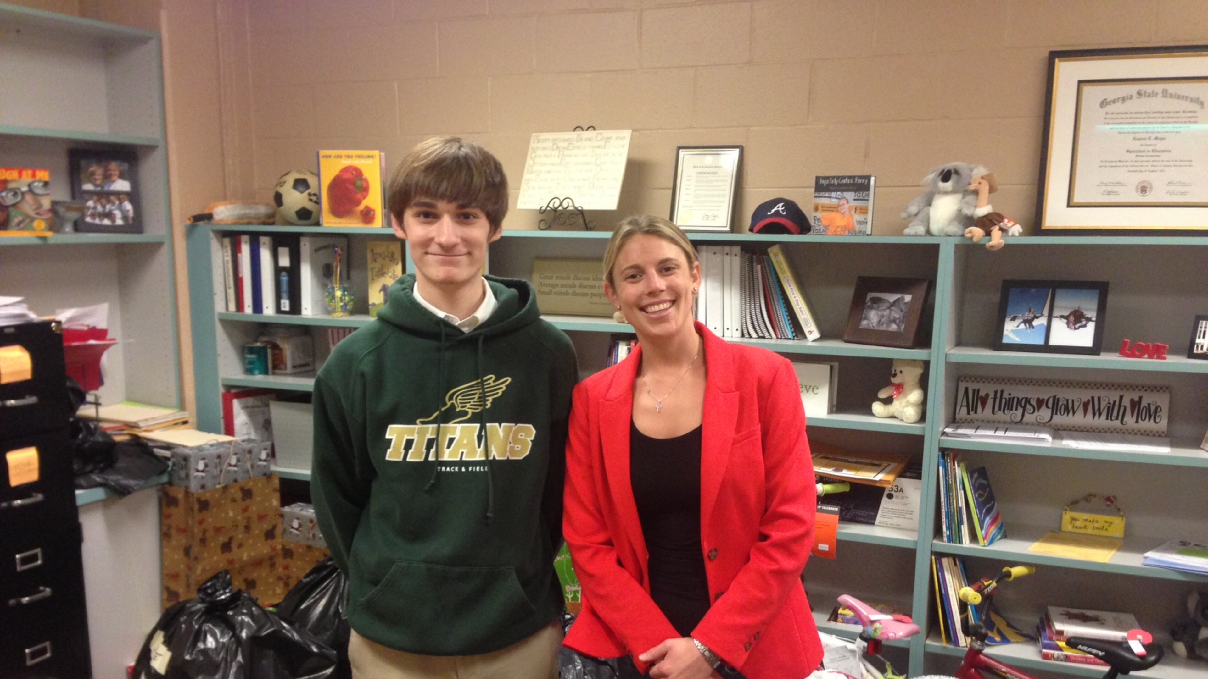 High school sophomore Luke Donovan and Counselor Laurie Meyer of Roswell North Elementary stand amid the bags holding hundreds of cold-weather clothes Donovan collected for children at the school.