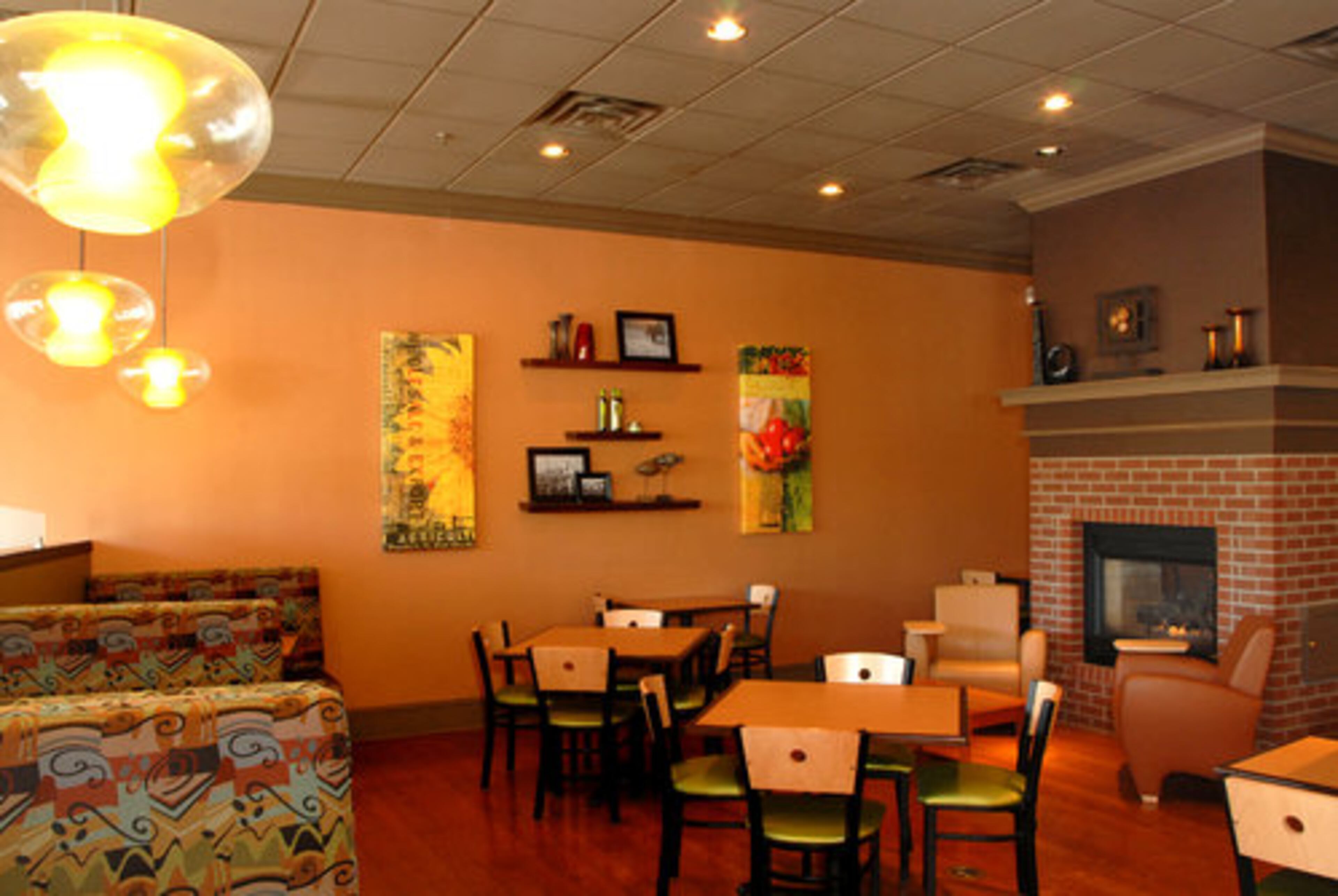 The new look (above) has more comfortable seating, softer green and red earth-tones and partitions that create smaller seating sections. The company hopes the remodeled stores invite people to linger during normally slow times, such as mid-morning and afternoon.