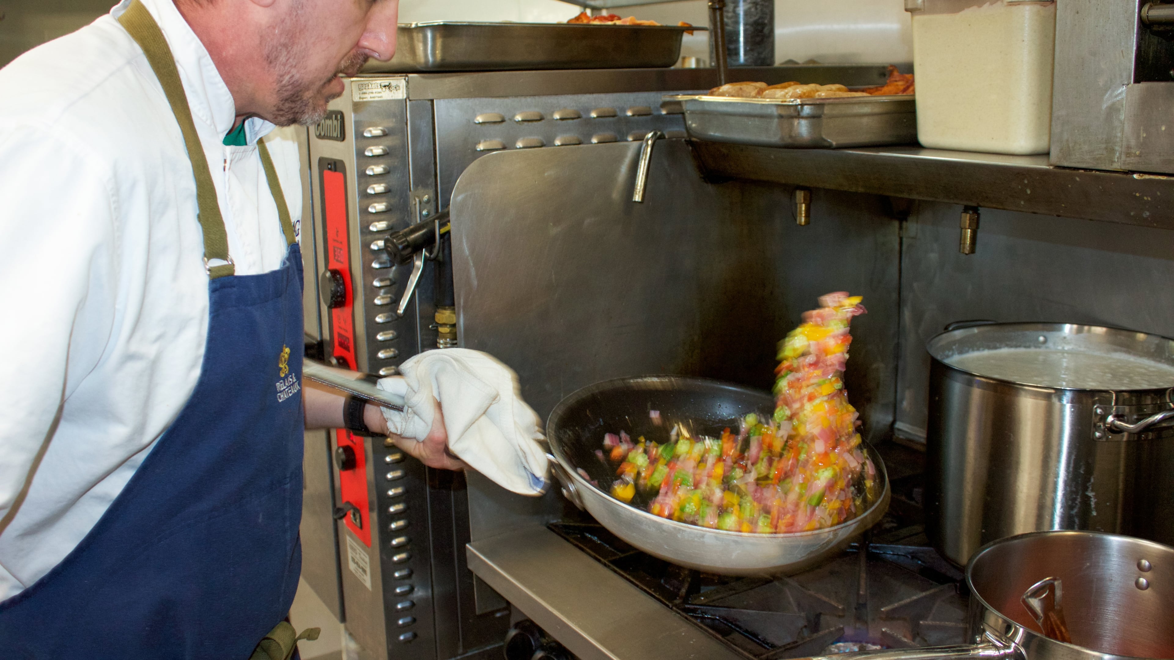 Chef Jake Schmidt of the Swag, a resort in Waynesville, North Carolina, prepares breakfast succotash with tomato gravy. The dish frequently changes to showcase seasonal, locally grown produce. (Courtesy of Becky Seymour)