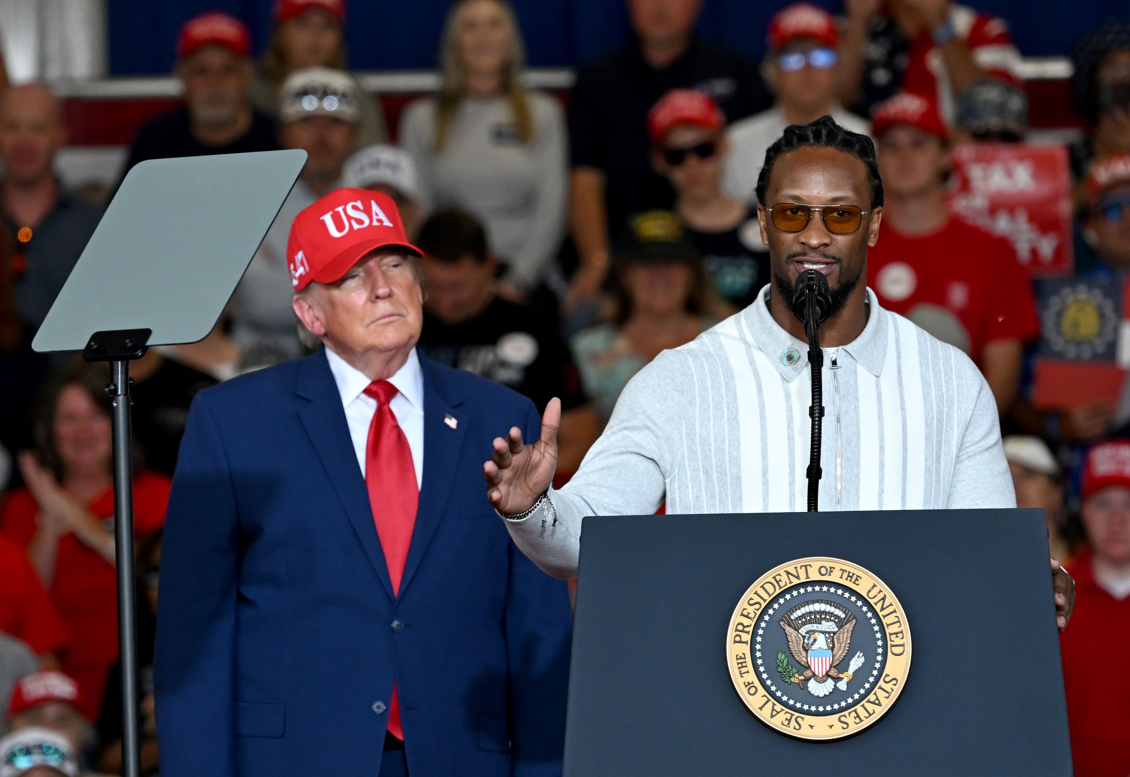 Former UGA star running back Todd Gurley speaks as President Donald Trump stands beside him during a campaign rally at Dalton Municipal Airport on Friday, Oct. 16, 2026, in Dalton. (Hyosub Shin/AJC)