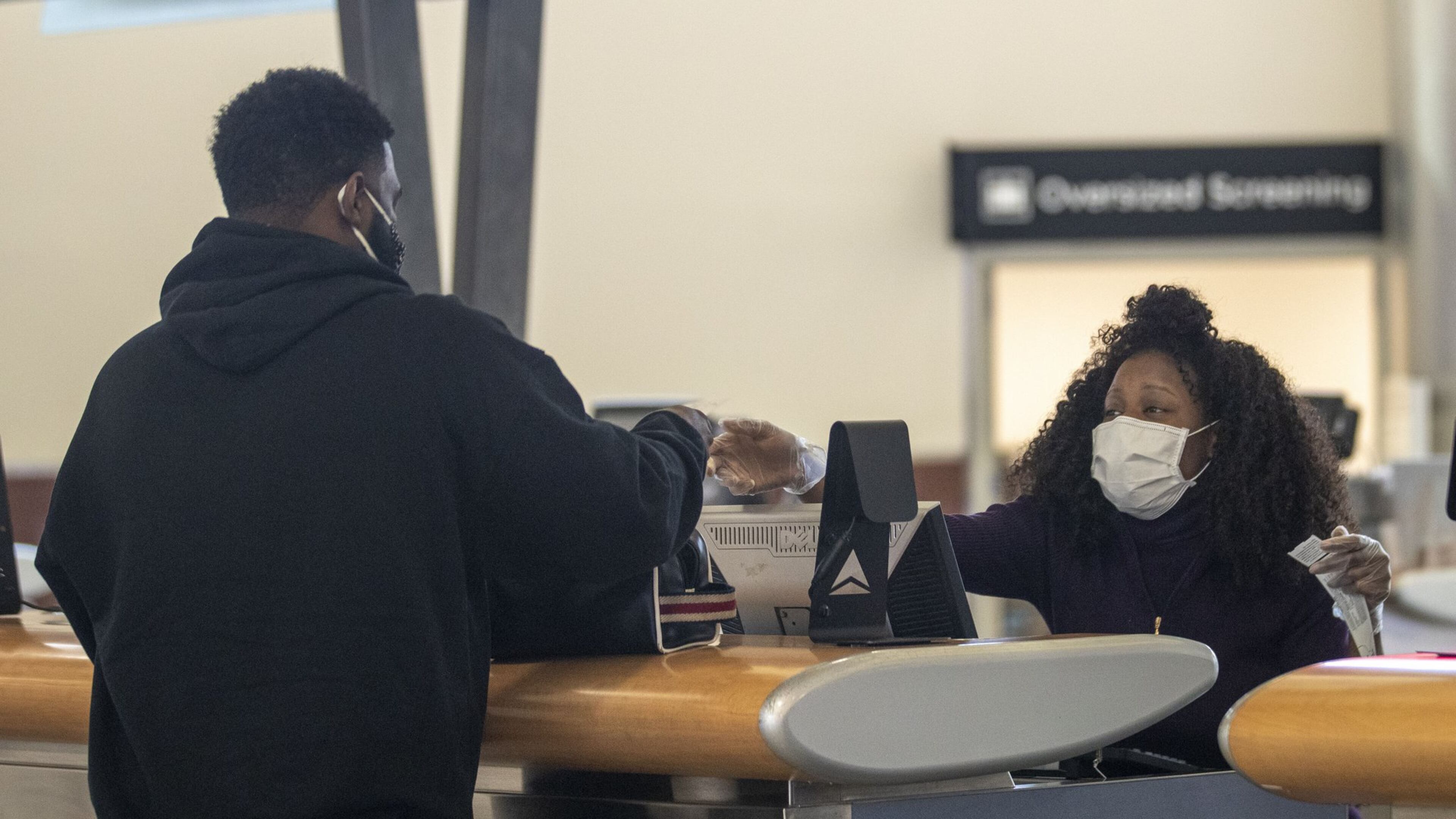 Wearing personal protective equipment, Delta Air Lines customer service agent Kim Franklin (right) communicates with a customer at a Delta Air Lines service desk inside Atlanta’s Hartsfield-Jackson International Airport. (ALYSSA POINTER / ALYSSA.POINTER@AJC.COM)