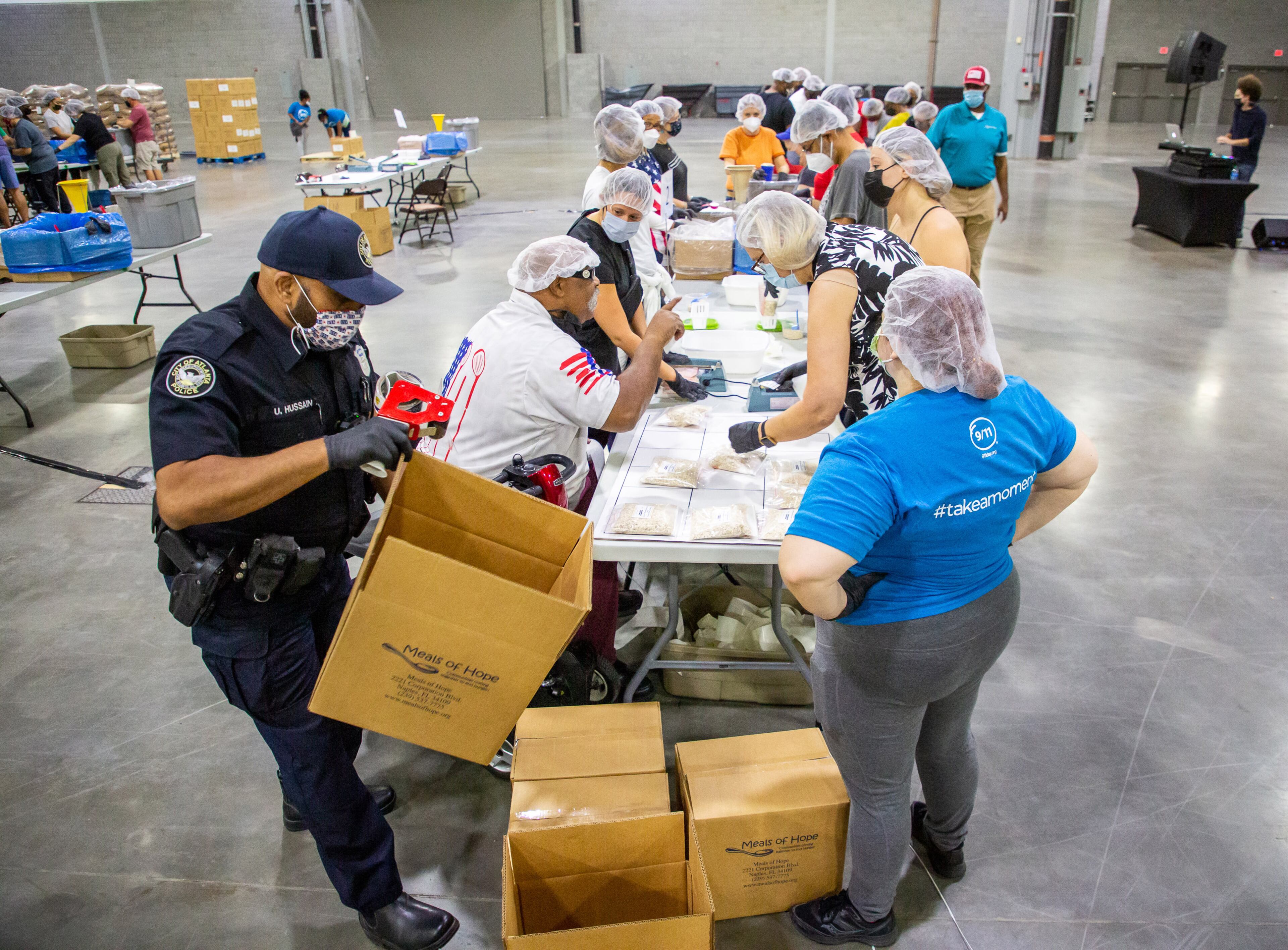 Atlanta Police officer U. Hussain (L) assembles boxes that will eventually hold 36 meals during the 9/11 National Day of Service at the Georgia World Congress Center on Saturday, September 11, 2021. During the event, hundreds of volunteers packed meals for the Atlanta Community Food Bank. STEVE SCHAEFER FOR THE ATLANTA JOURNAL-CONSTITUTION