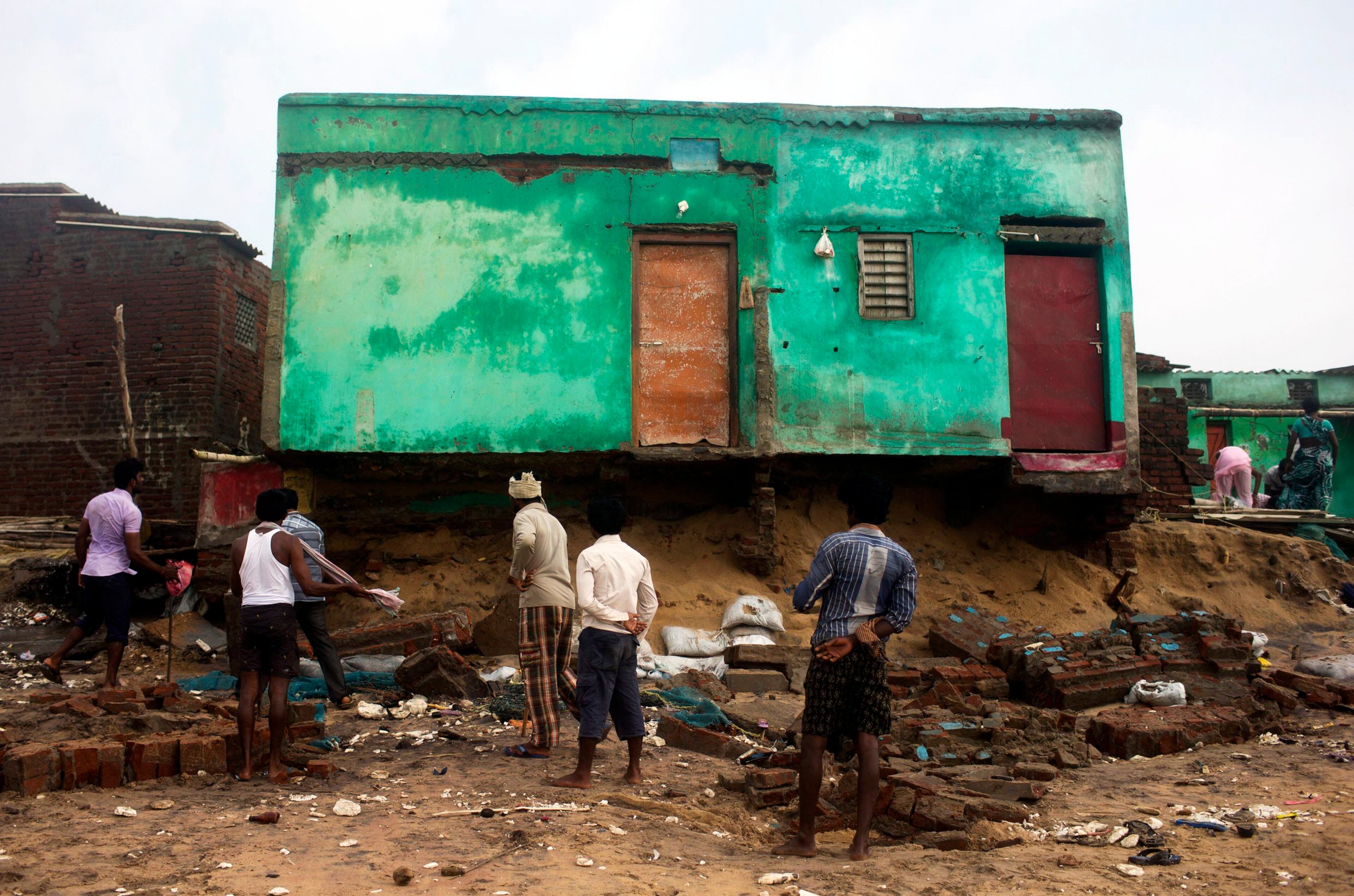 Fishermen clear debris from their damaged houses after Cyclone Phailin hit Puri in the eastern Indian state of Odisha October 14, 2013. A mass evacuation saved thousands of people from India's fiercest cyclone in 14 years, but aid workers warned a million would need help after their homes and livelihoods were destroyed. Cyclone Phailin was expected to dissipate within 36 hours, losing momentum on Sunday as it headed inland after making landfall from the Bay of Bengal, bringing winds of more than 200 kph (125 mph) that ripped apart tens of thousands of thatched huts, mangled power lines and tore down trees. REUTERS/Ahmad Masood