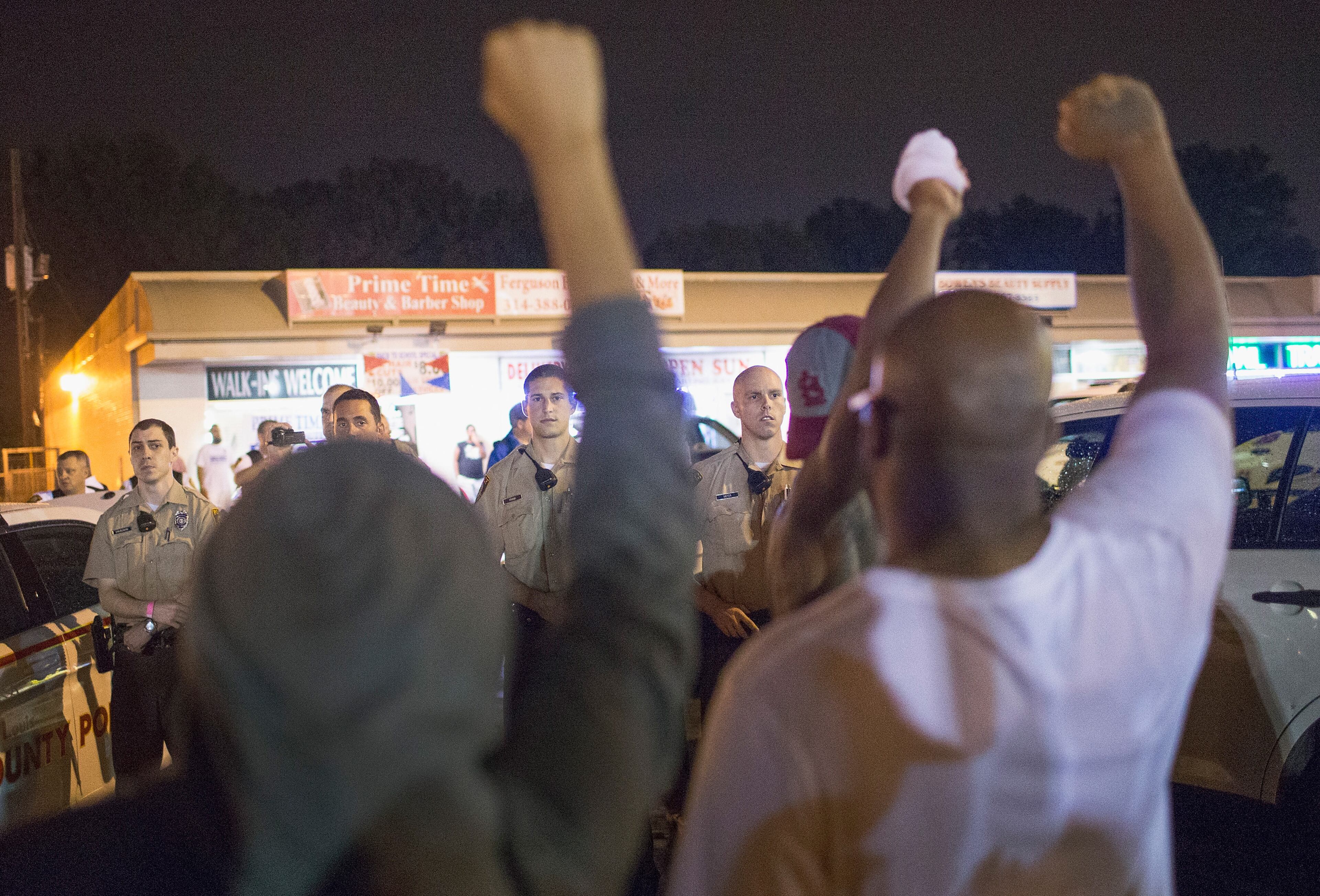 FERGUSON, MO - AUGUST 09: Demonstrators, marking the one-year anniversary of the shooting of Michael Brown, face off with police during a protest along West Florrisant Street on August 9, 2015 in Ferguson, Missouri. There are reports that two people were shot when gun fire broke out during protests later in the evening. Brown was shot and killed by a Ferguson police officer on August 9, 2014. His death sparked months of sometimes violent protests in Ferguson and drew nationwide focus on police treatment of black offenders. (Photo by Scott Olson/Getty Images)