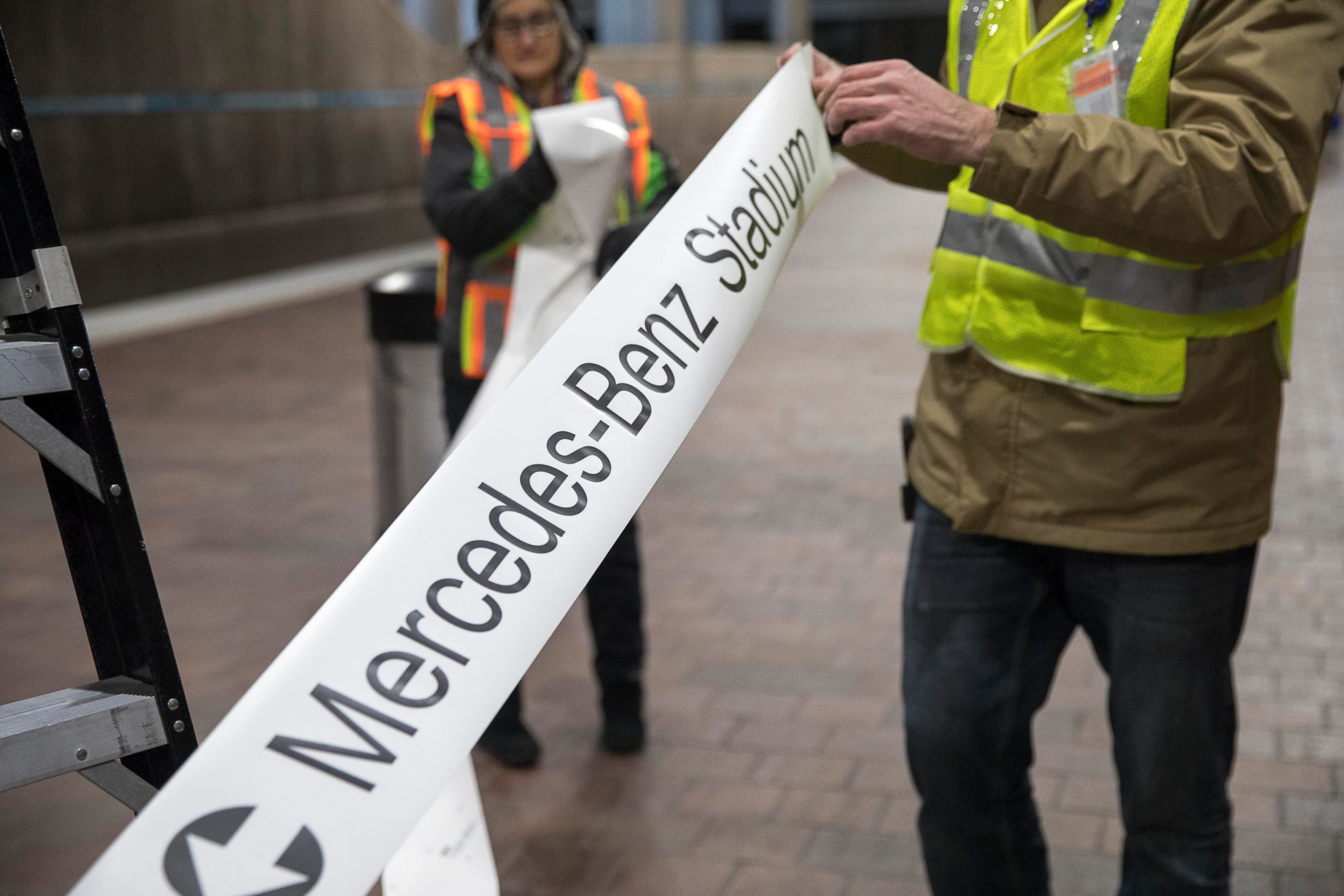 01/16/2019 -- Atlanta, Georgia -- Employees of Advantage Graphics & Signs roll out the new signage that will direct attendees to Mercedes-Benz Stadium at the MARTA Dome/GWCC/Philips Arena/CNN Center Transit in Atlanta, Wednesday, January 16, 2019. Advantage Graphics & Signs worked in the transit station on Wednesday to replace signage that mislabeled Atlanta's two newly named sport stadiums. (ALYSSA POINTER/ALYSSA.POINTER@AJC.COM)
