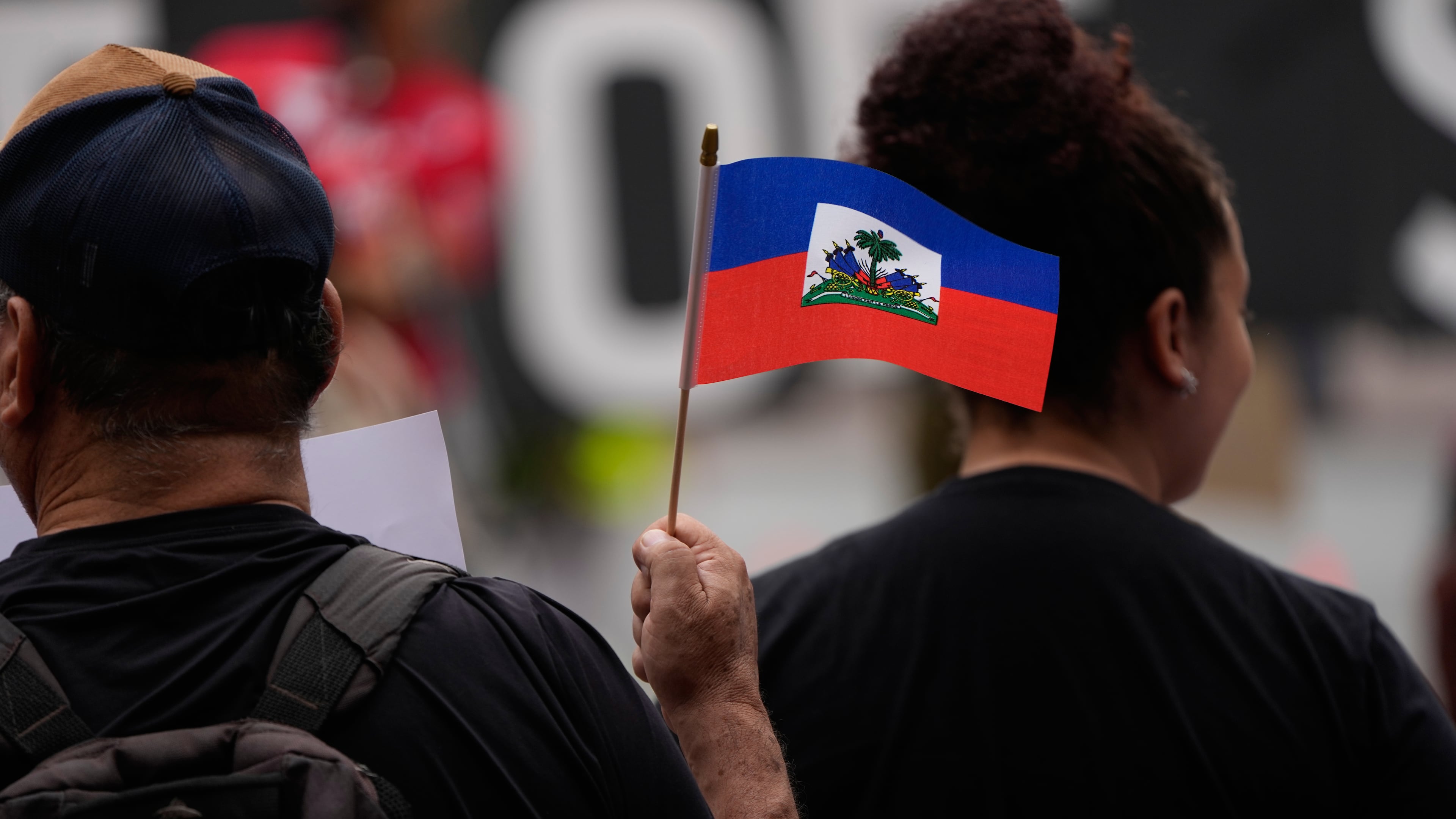 People hold Haitian flags and signs during a rally in support of immigrants living in the United States with temporary protected status on Thursday, July 9, 2026, in San Diego. (Gregory Bull/AP)