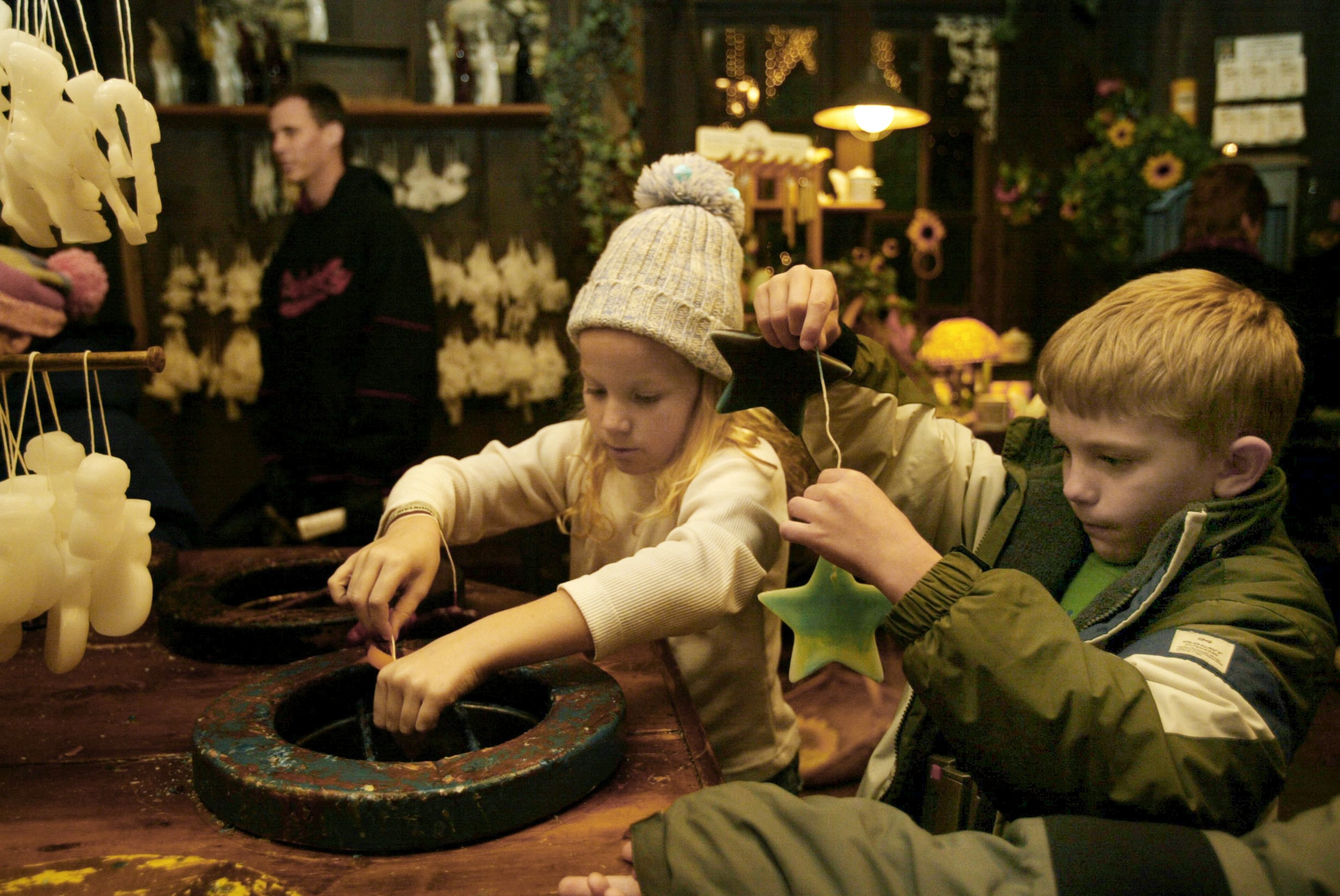 Getting out of the cold, 9-year-old Lydia Bowman, left, of Cartersville, and 8-year-old Cade Minton, right, of Flowery Branch, dip candles in color at Stone Mountain Park's Southern Christmas. (FILE)