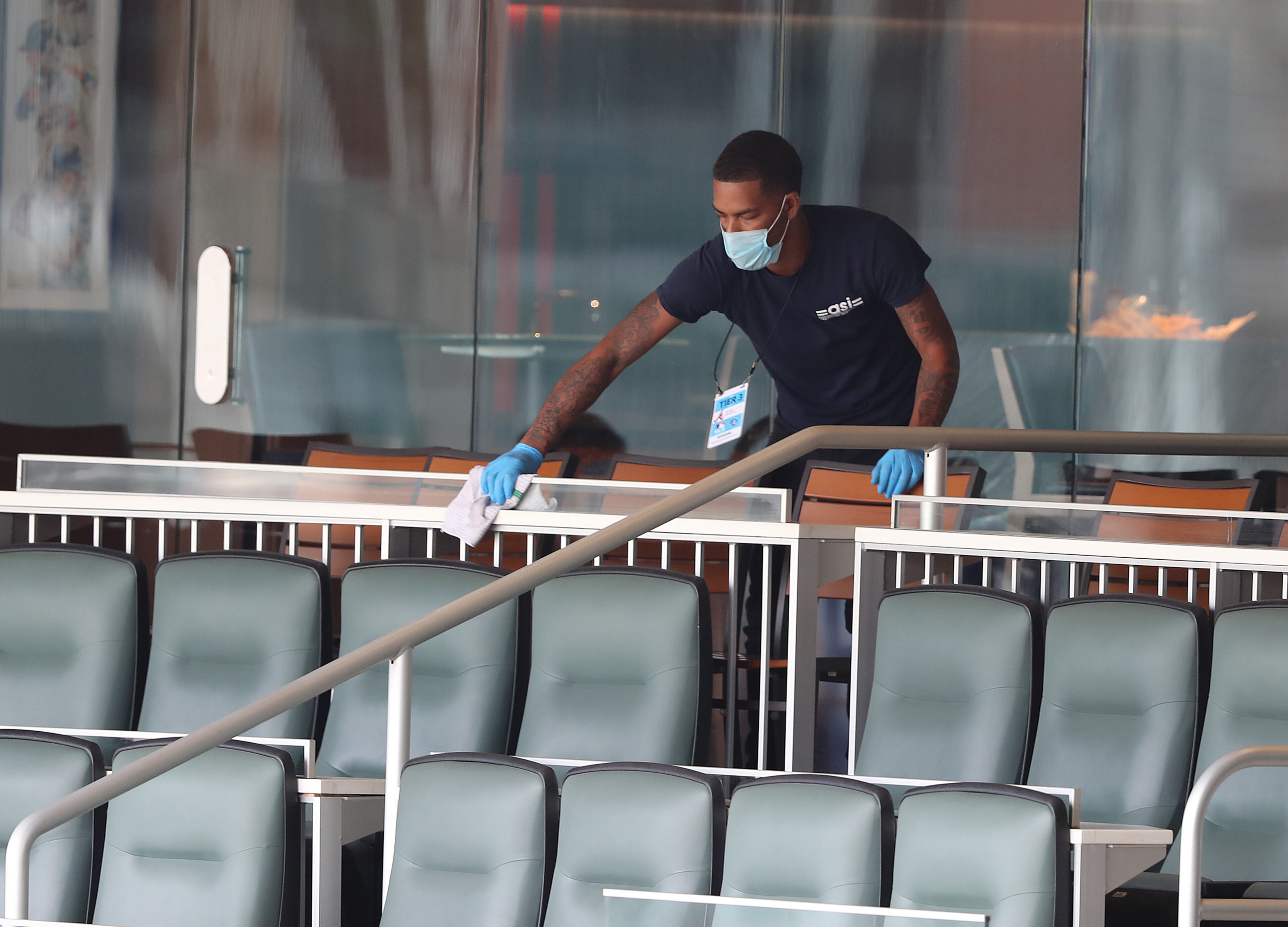 Despite the absence of fans, a Braves employee still cleans some seats prior to Wednesday's home opener at Truist Park. (Curtis Compton/ccompton@ajc.com)